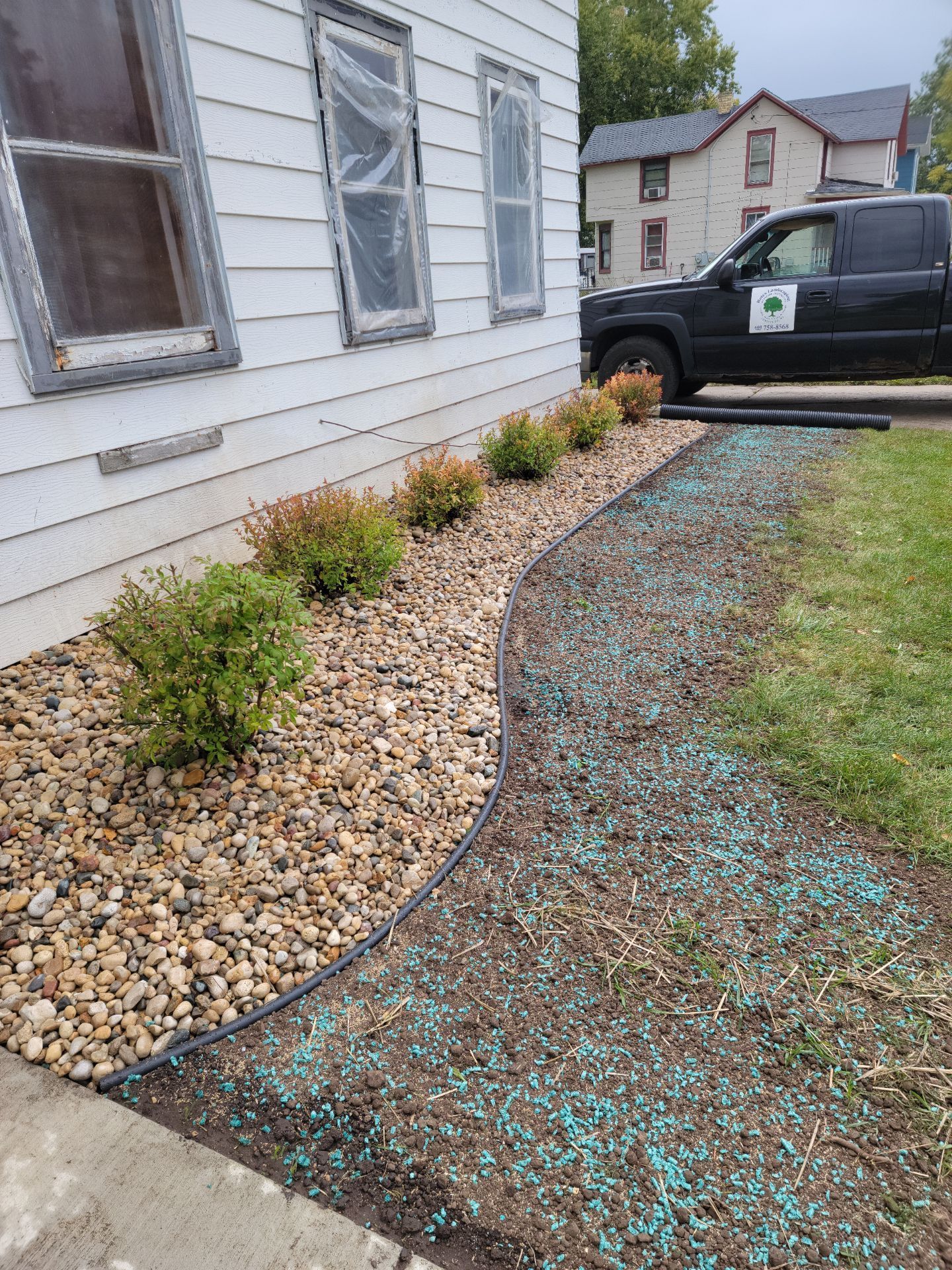 A black truck is parked in front of a white house.