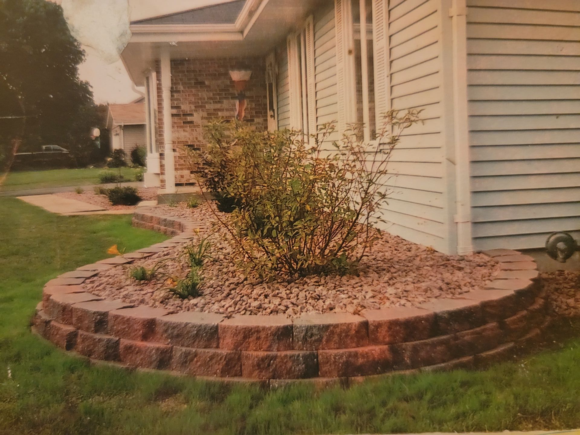 A house with a brick planter retaining wall in front of it