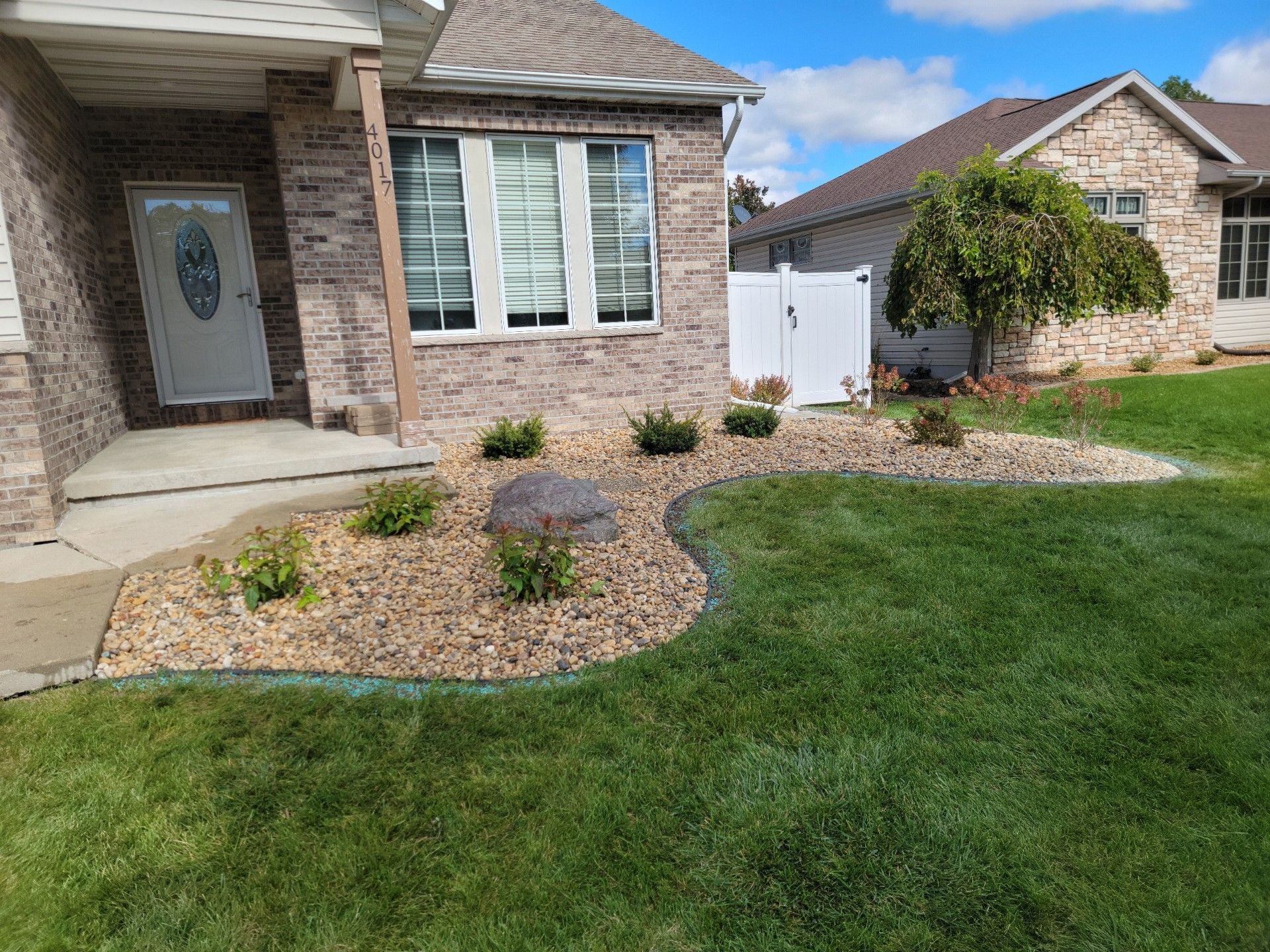 A brick house with a lush green shrubs in front of it.