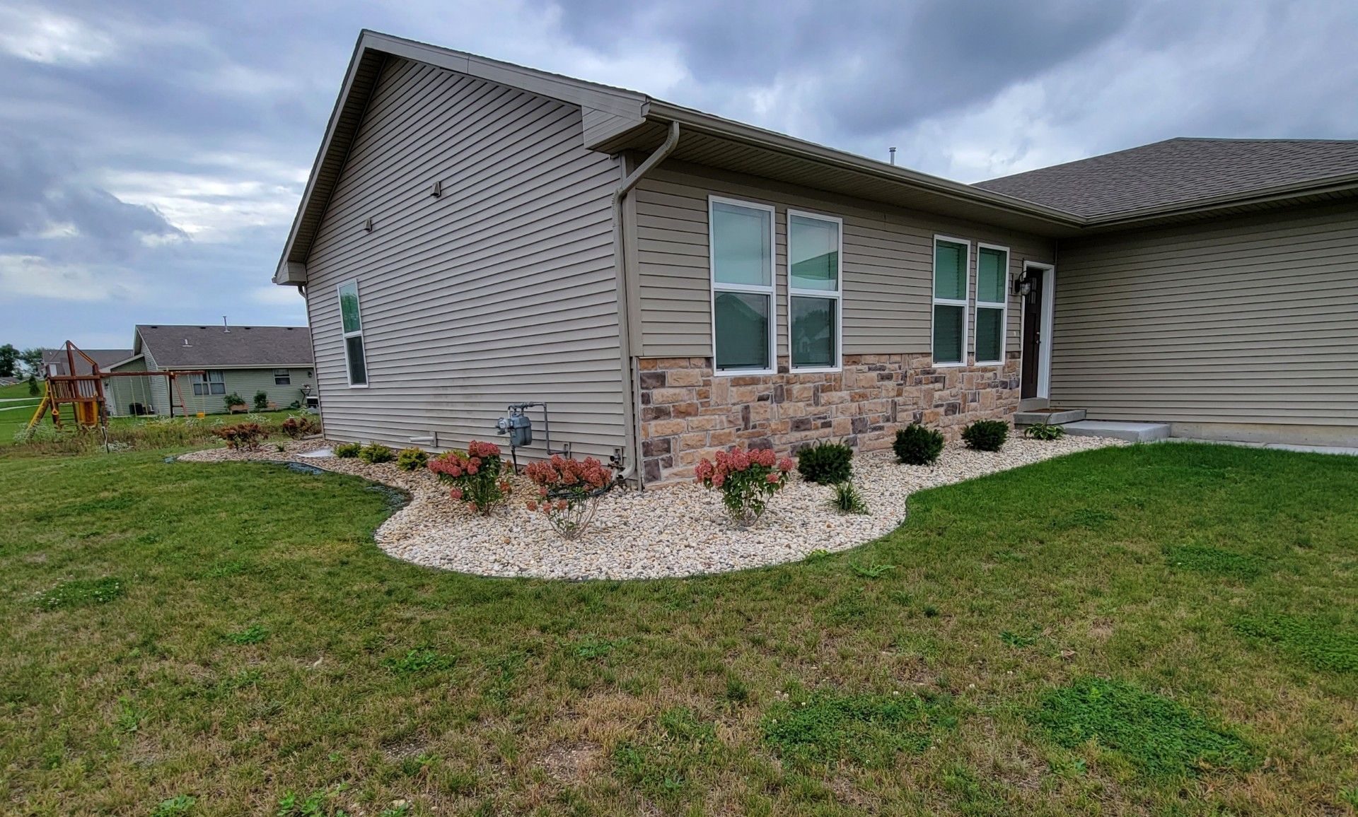 A house with a lush green lawn in front of it and renovated landscaping.