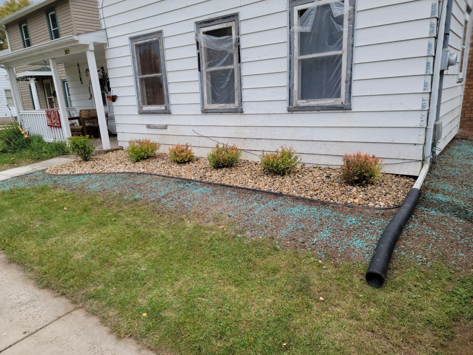 A white house with a drain pipe in front of it.