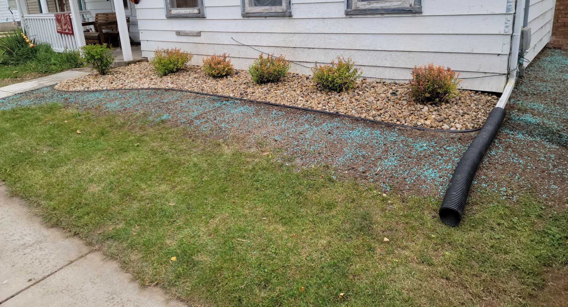 A white house with a lawn and a drain pipe in front of it.