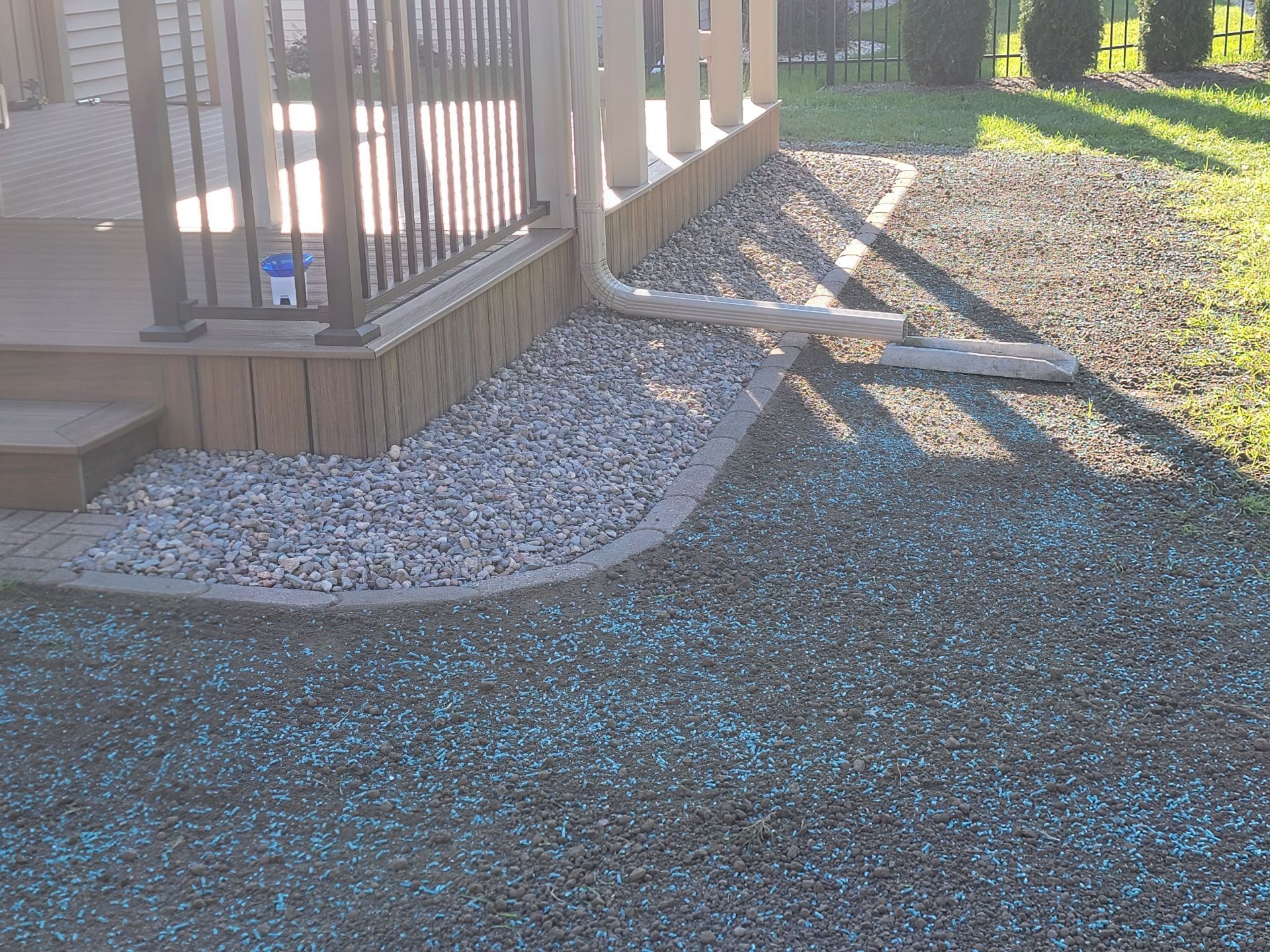 A gravel path leading to a deck with a fence in the background.