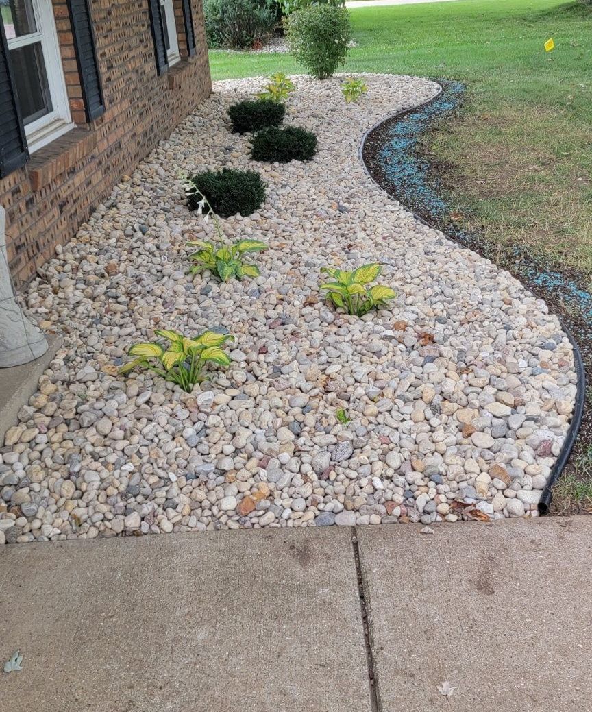 A garden with rocks and plants in front of a house.