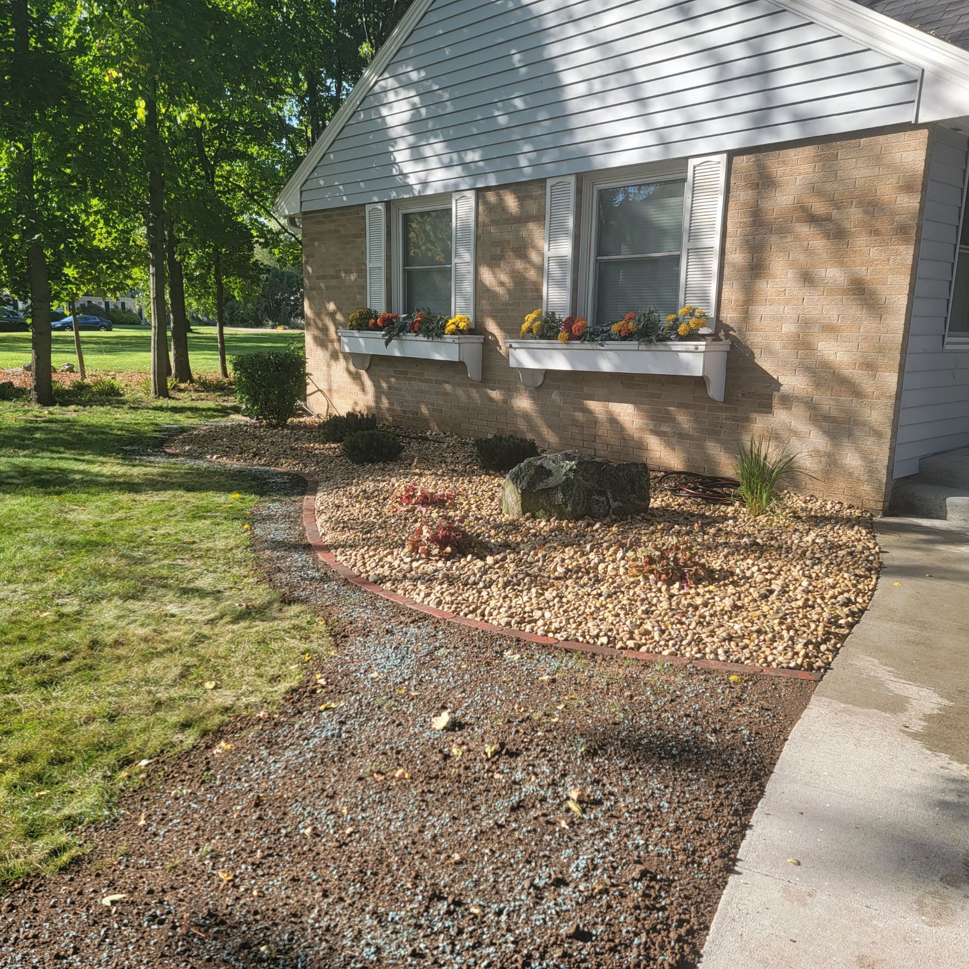 A house with planted flowers in the windows and shrubs in yard