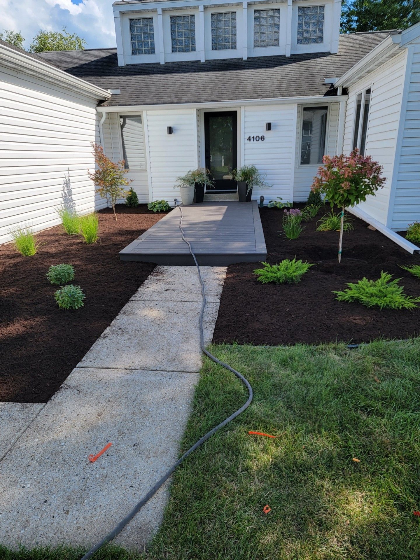 A white house with a brick walkway leading to the front door.