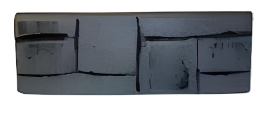 Damaged gray rectangular object with visible cracks and sections.