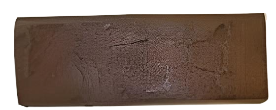 A rectangular, brown, textured object with a rounded edge and a crack running across it.