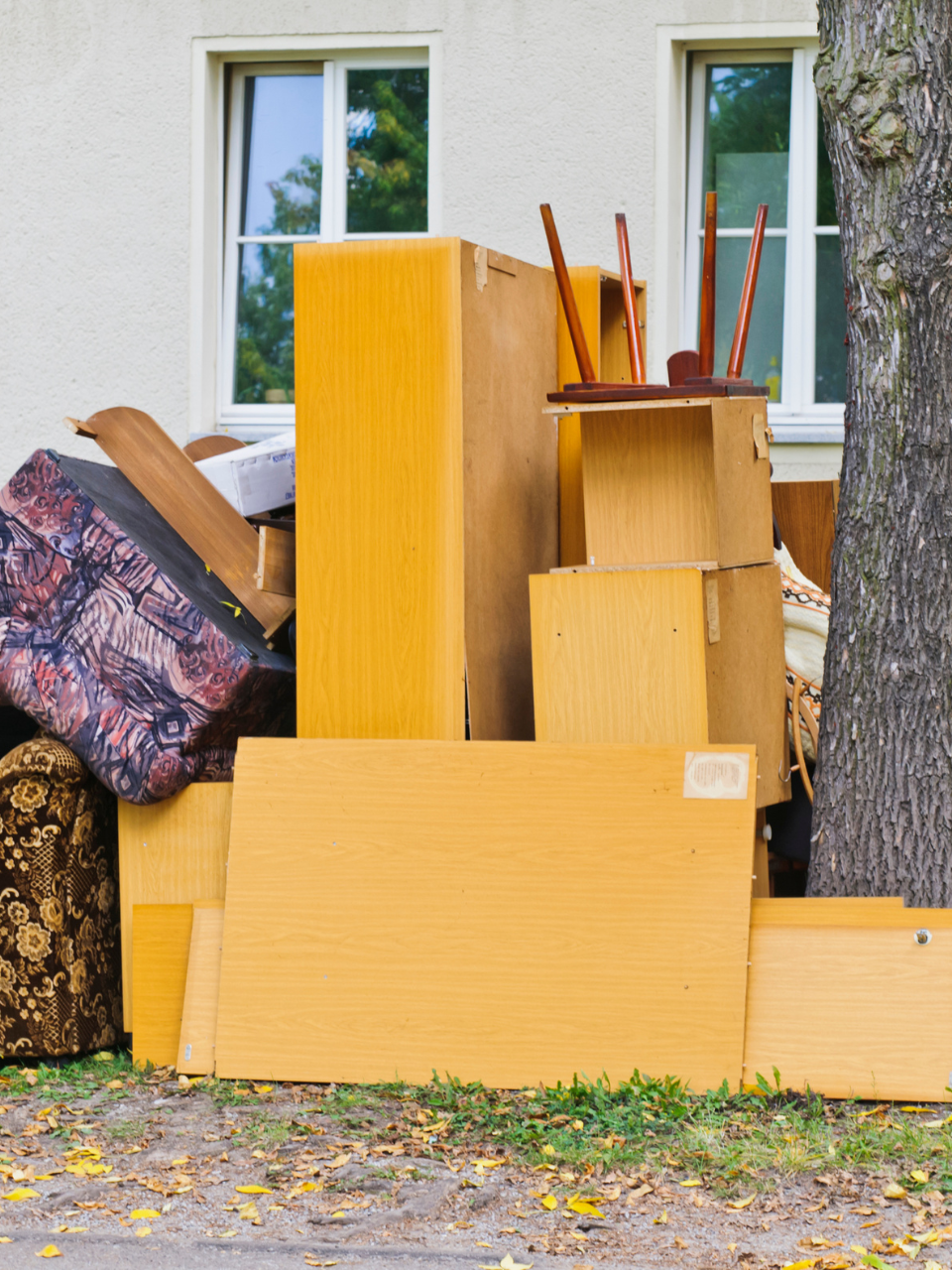 A pile of cardboard boxes and furniture in front of a house
