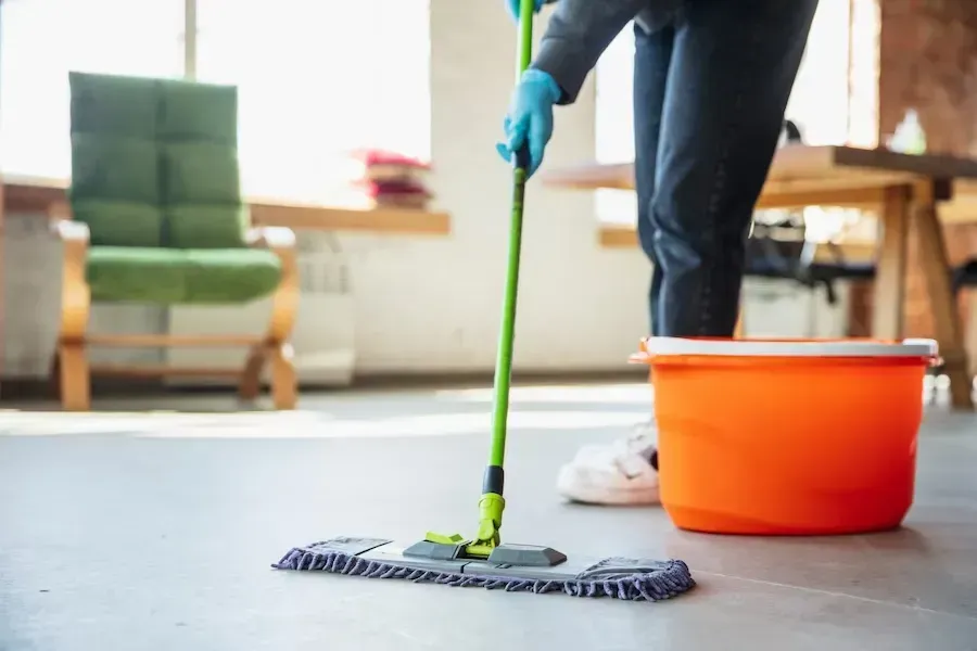 A person is cleaning the floor with a mop and bucket.