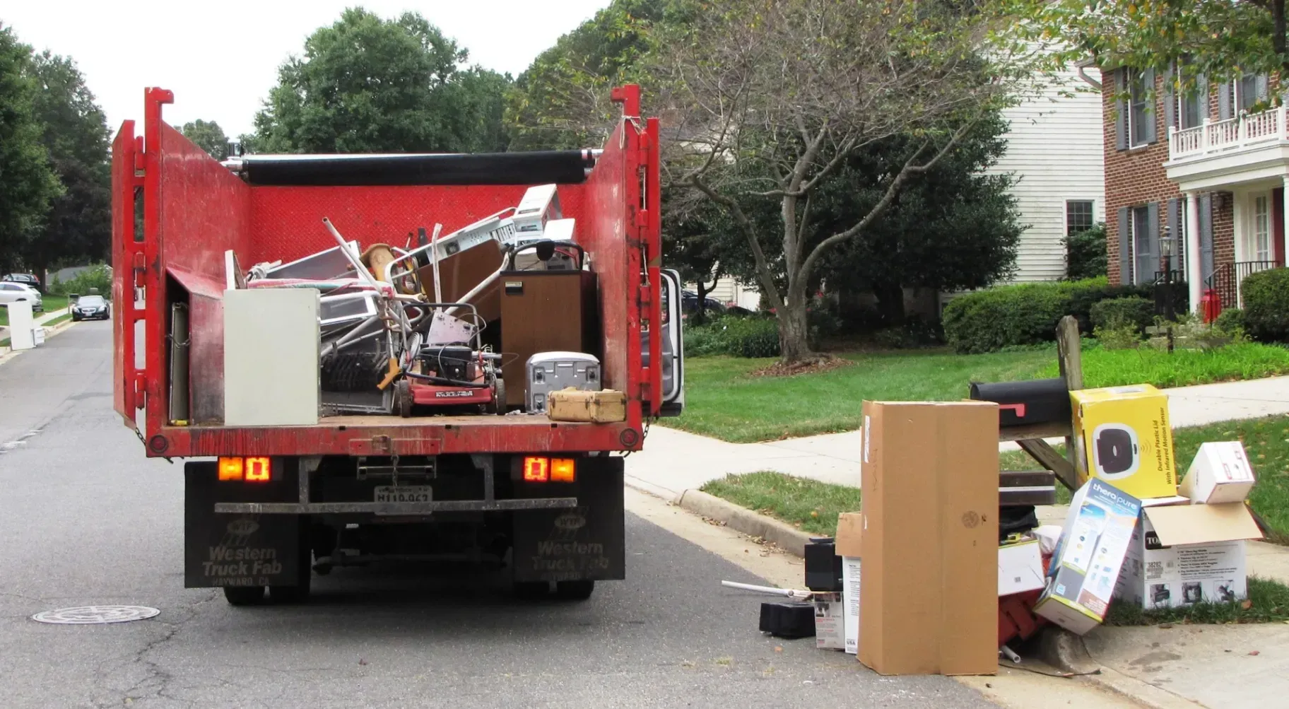 A red dumpster truck is full of junk on the side of the road
