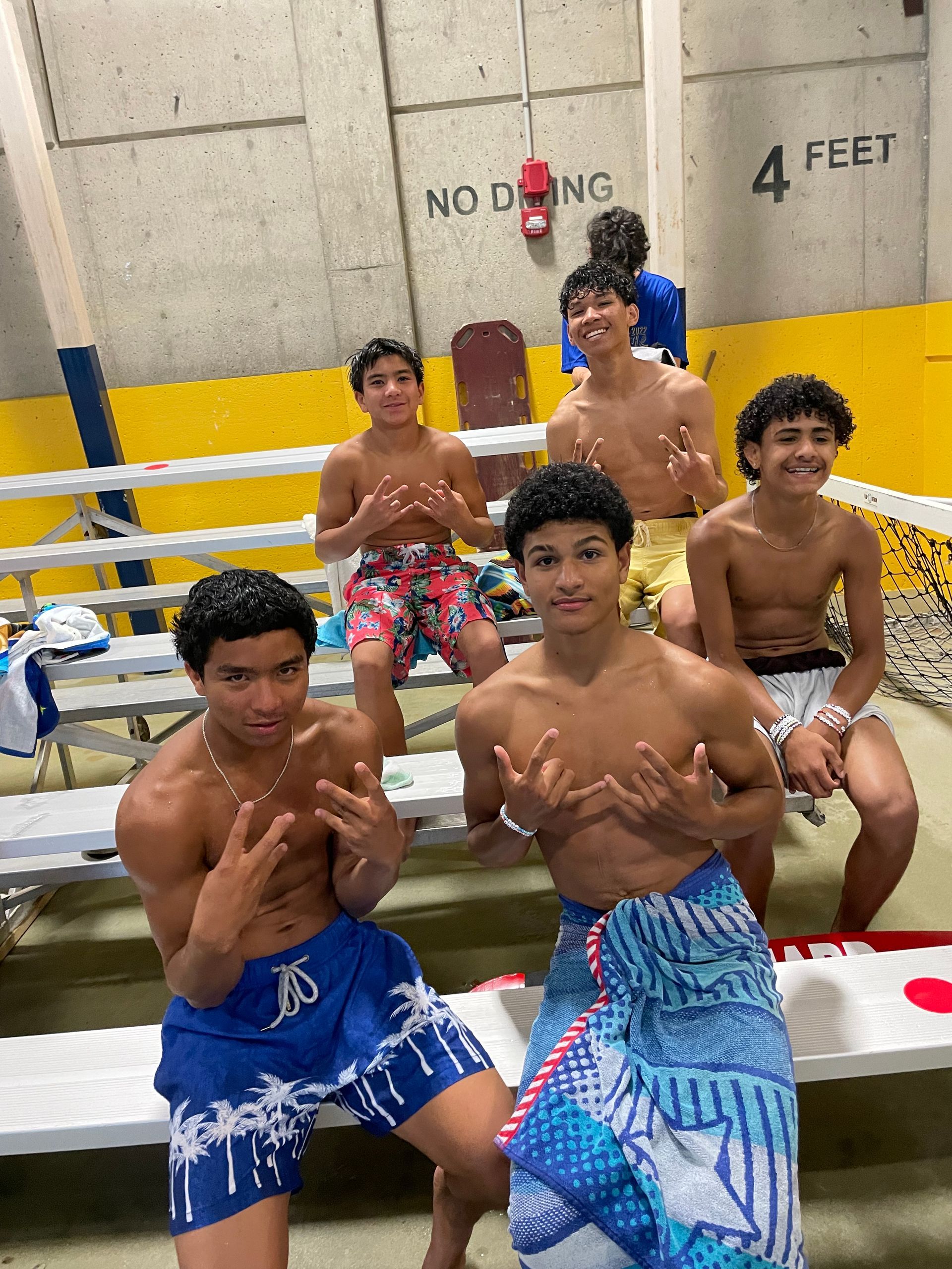 A group of young men are sitting on bleachers in a gym.