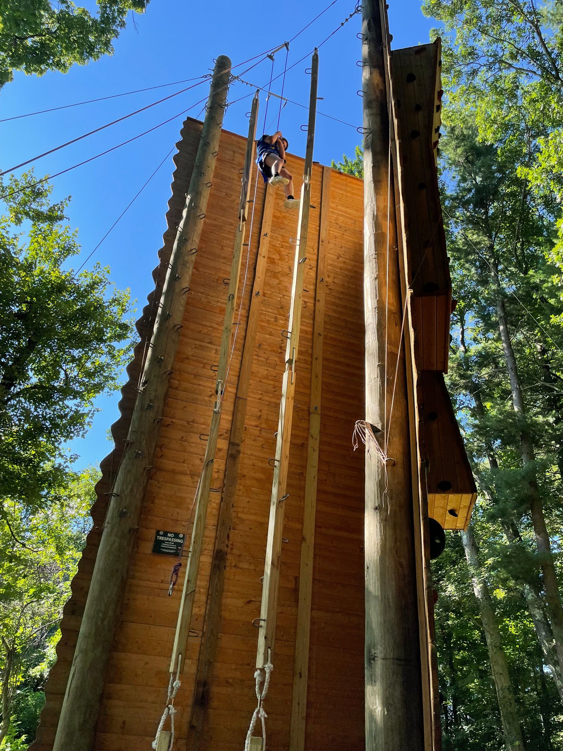 A man is climbing a very tall wooden wall