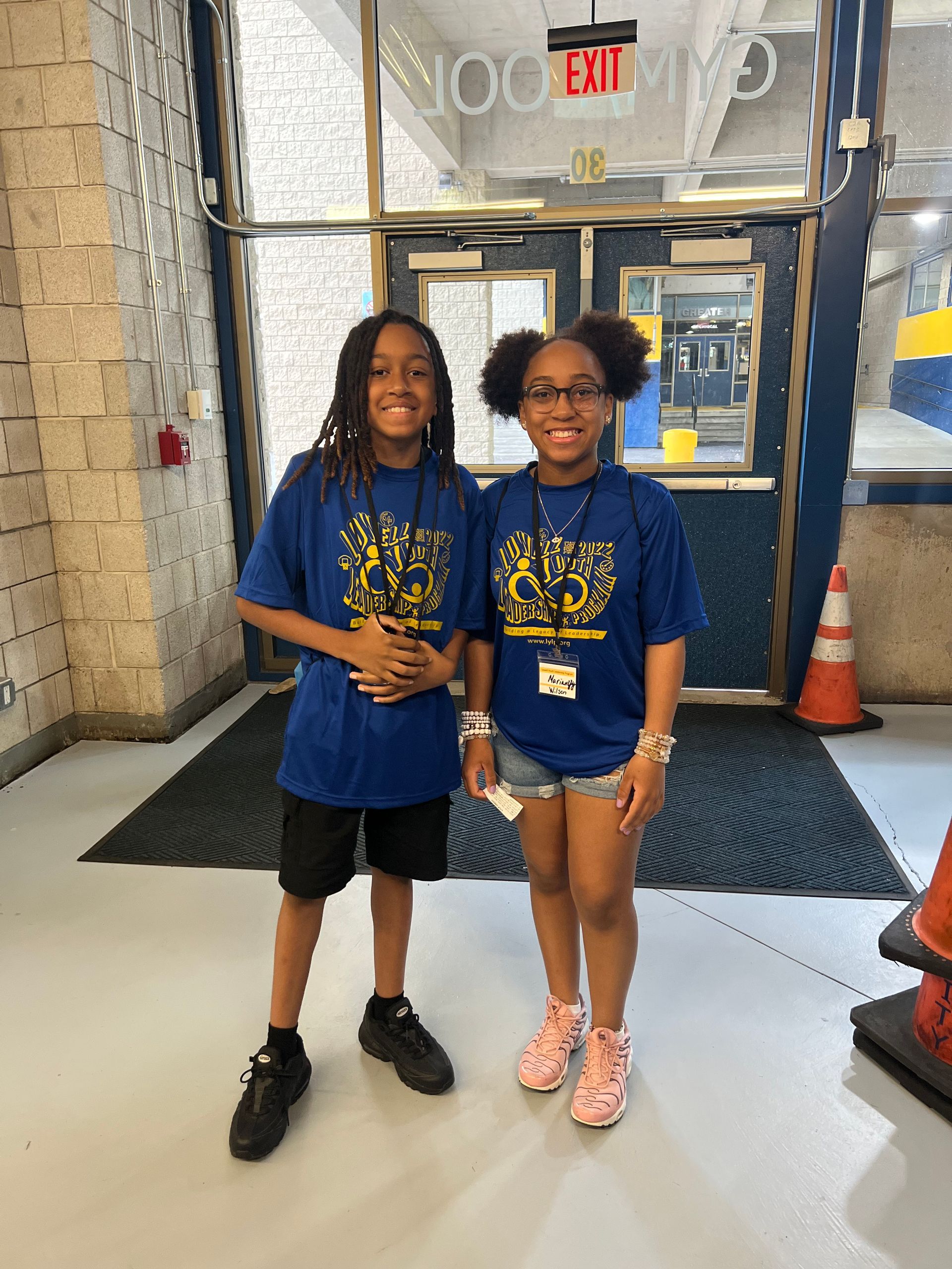 A boy and a girl are posing for a picture in front of a building.