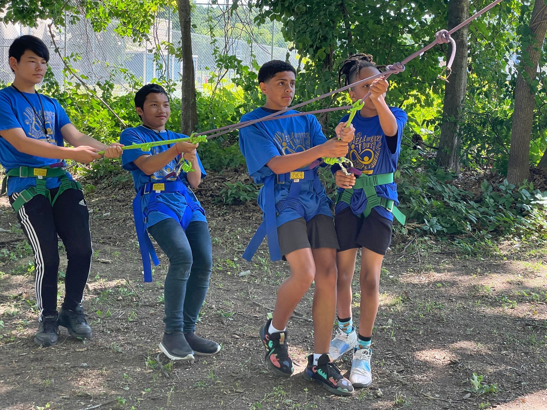 A group of children are playing with a rope in the woods.