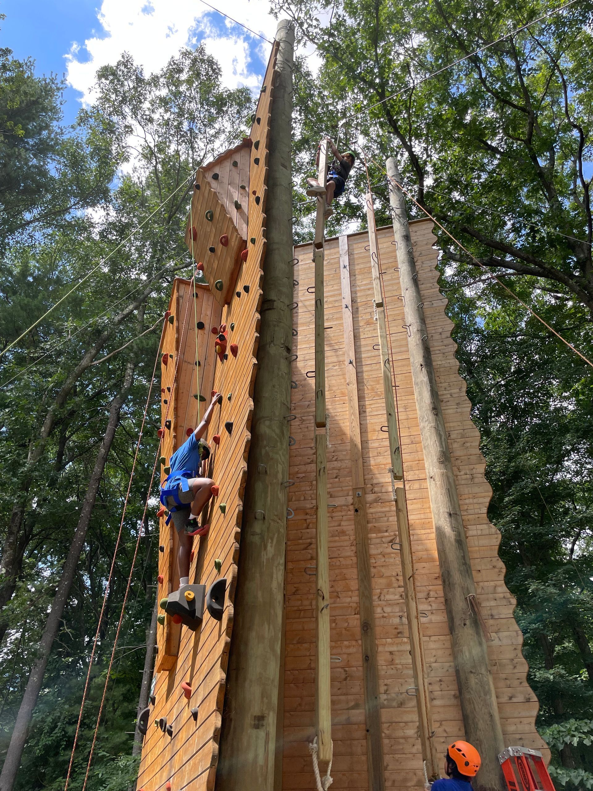 A man is climbing up a wooden climbing wall