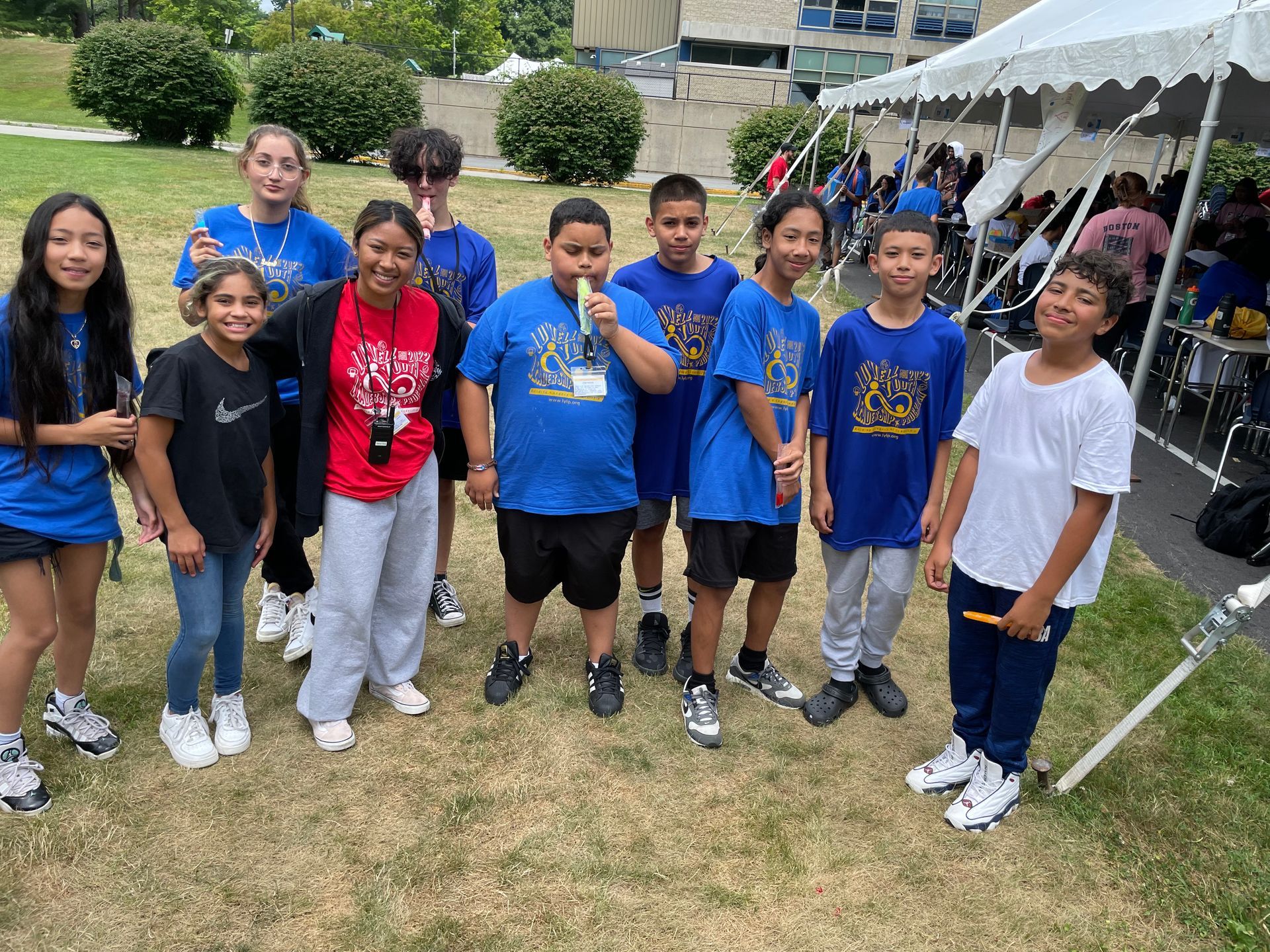 A group of young people are posing for a picture in front of a tent.