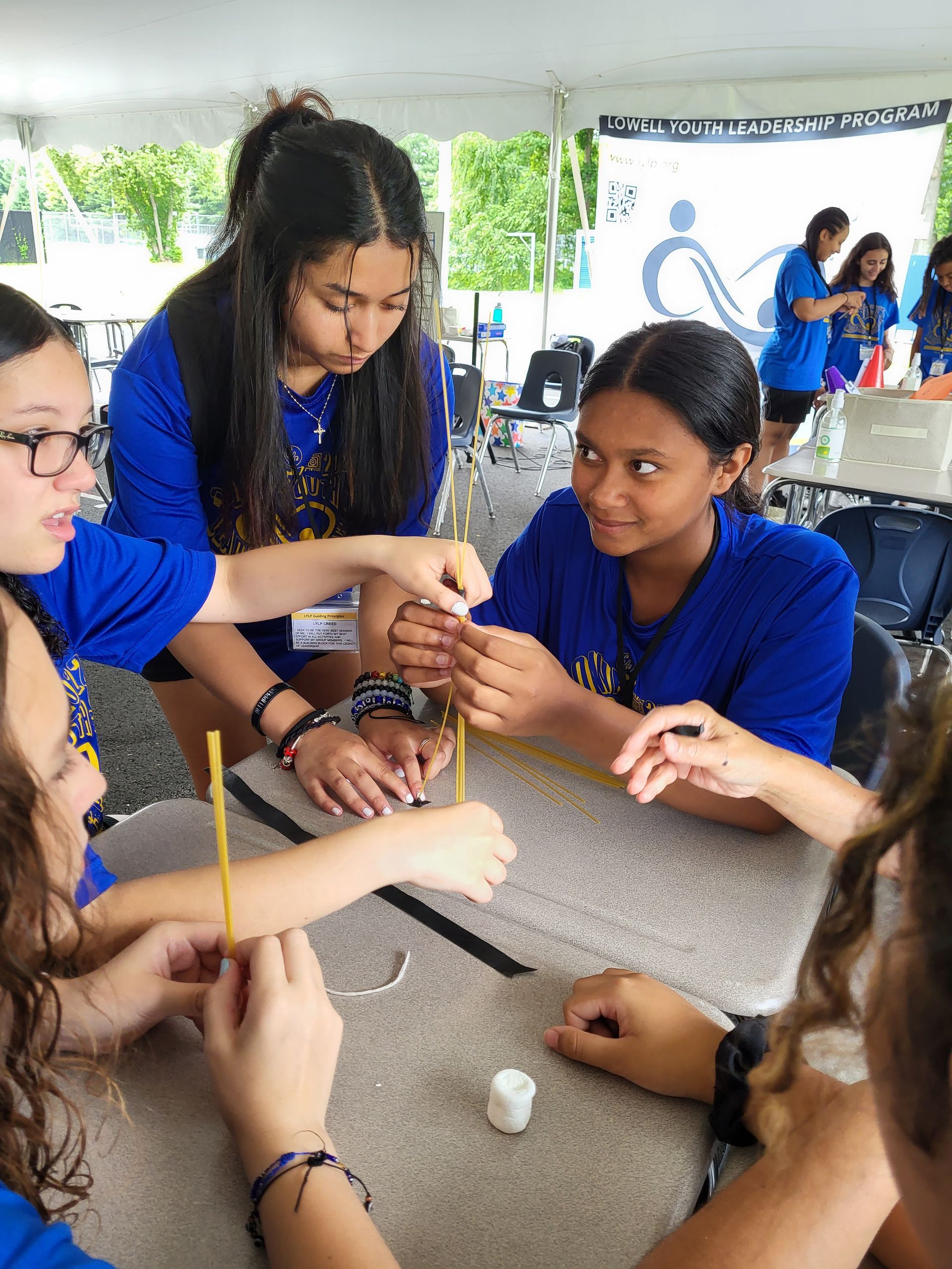 A group of young girls are sitting around a table working on a project.