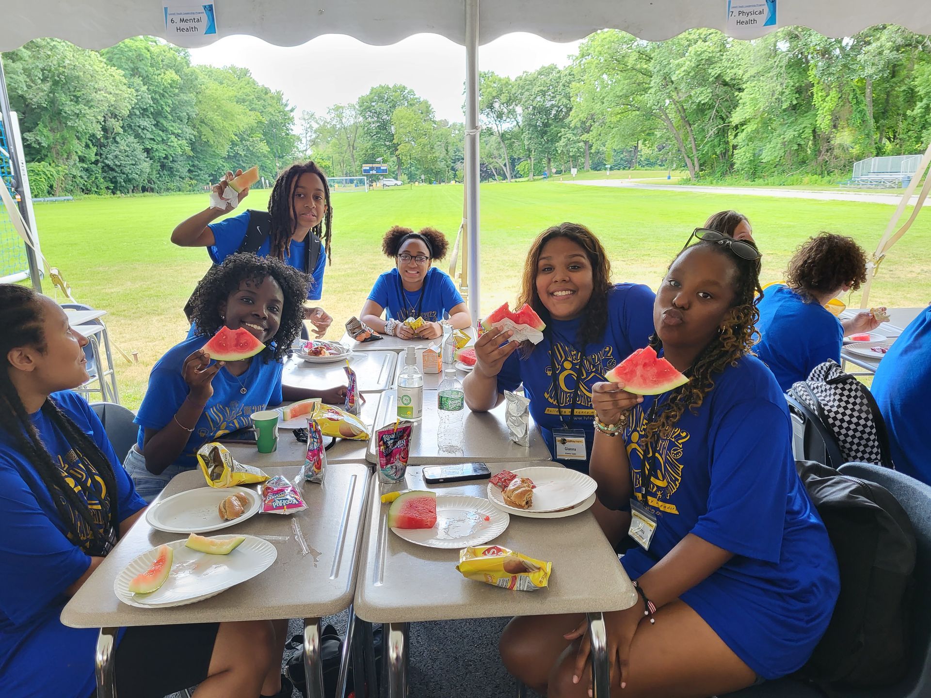 A group of women are sitting at a table eating watermelon.