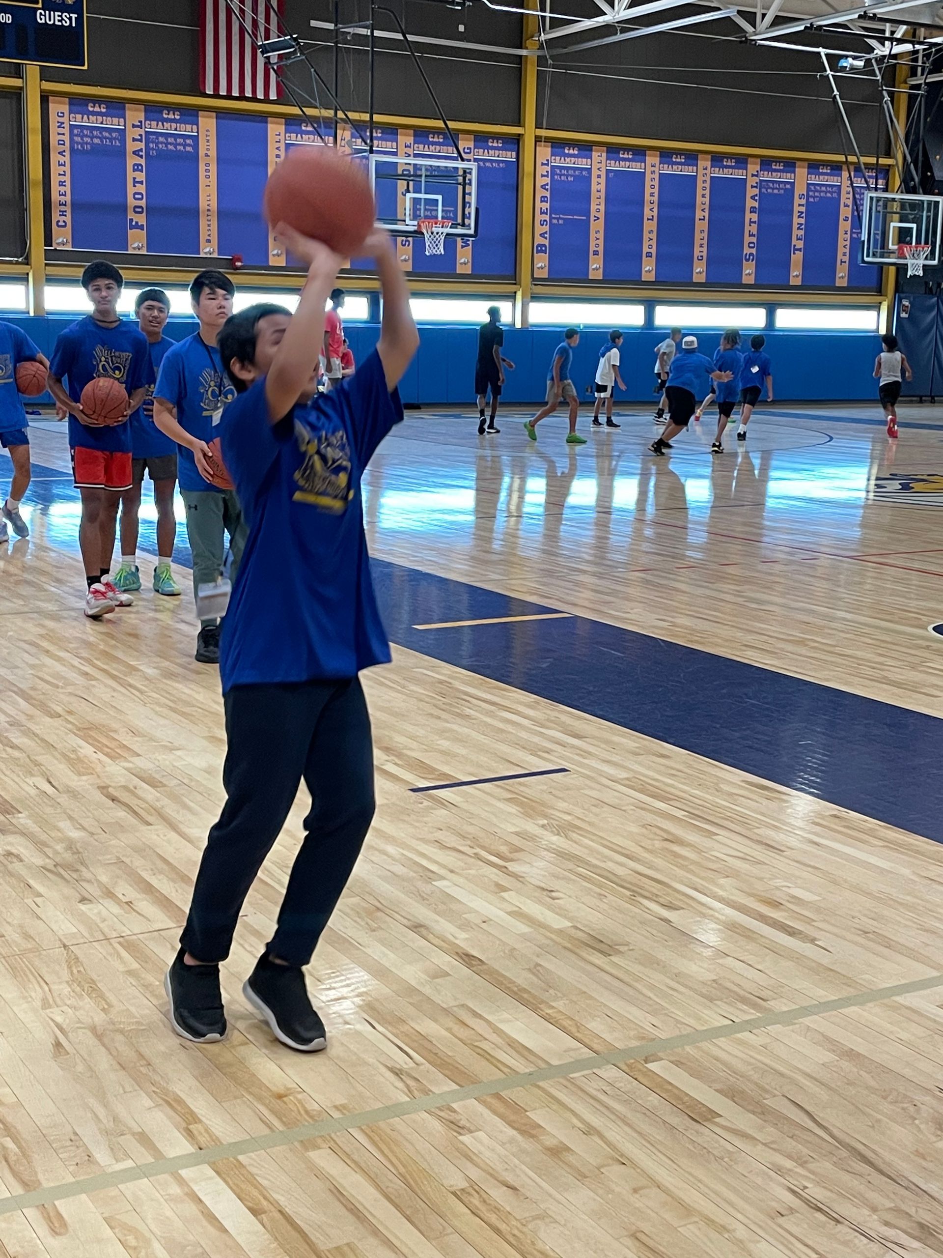 A boy in a blue shirt is holding a basketball over his head