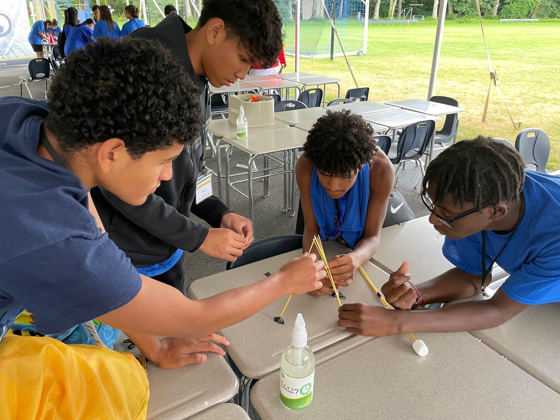 A group of young men are sitting at a table working on a project.