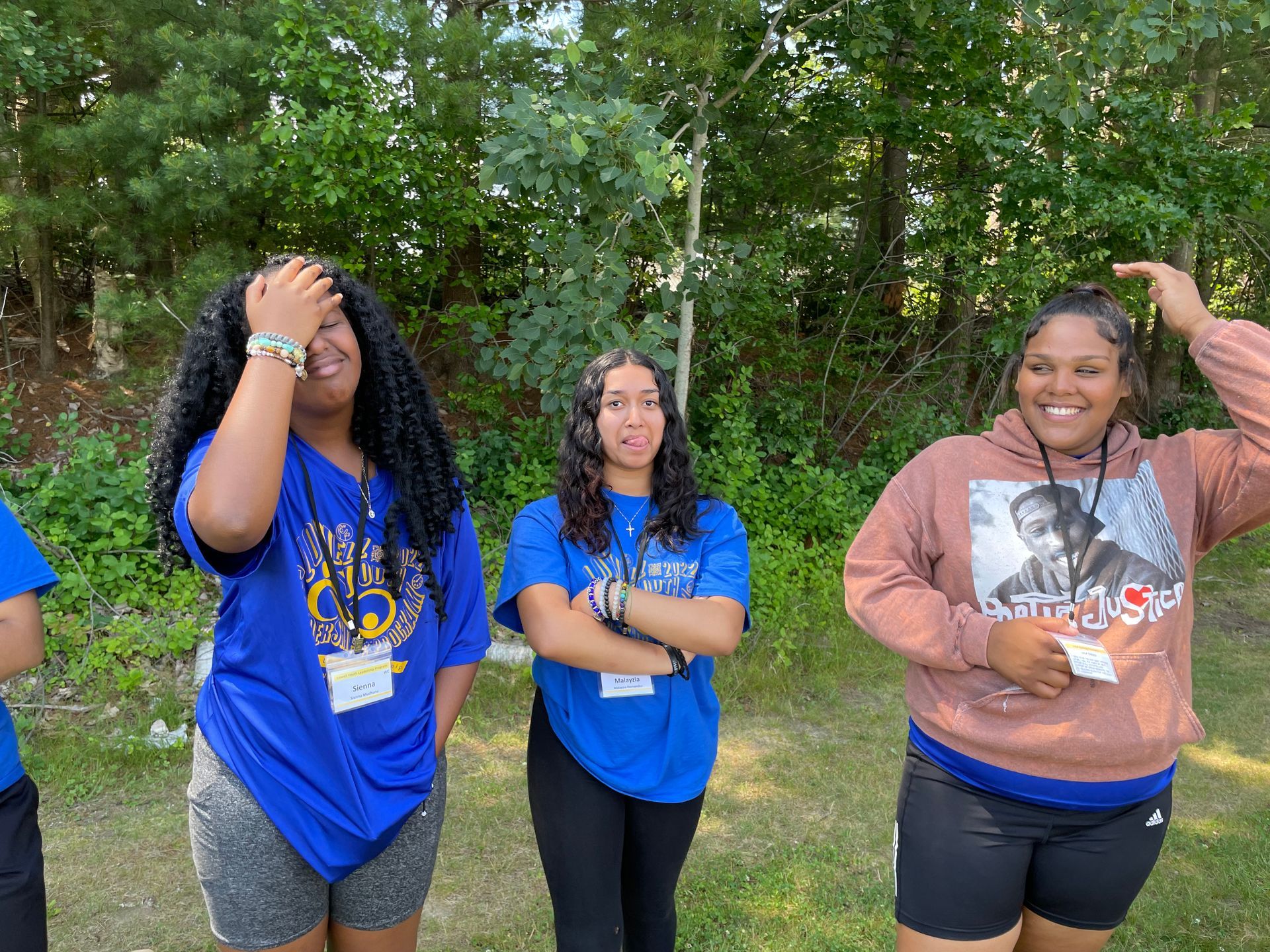 A group of young women are standing next to each other in front of trees.