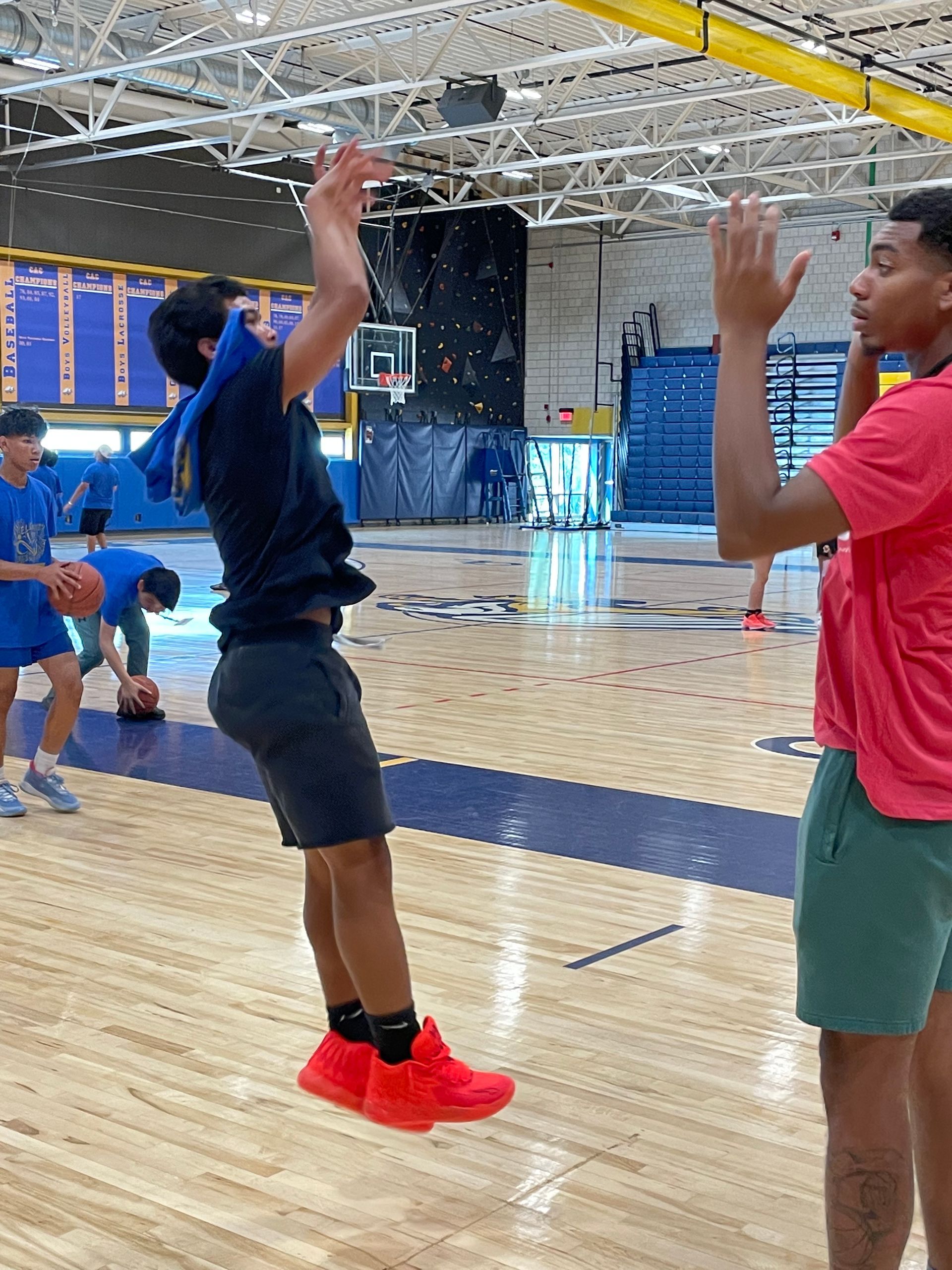 A man in red shoes is jumping in the air on a basketball court.