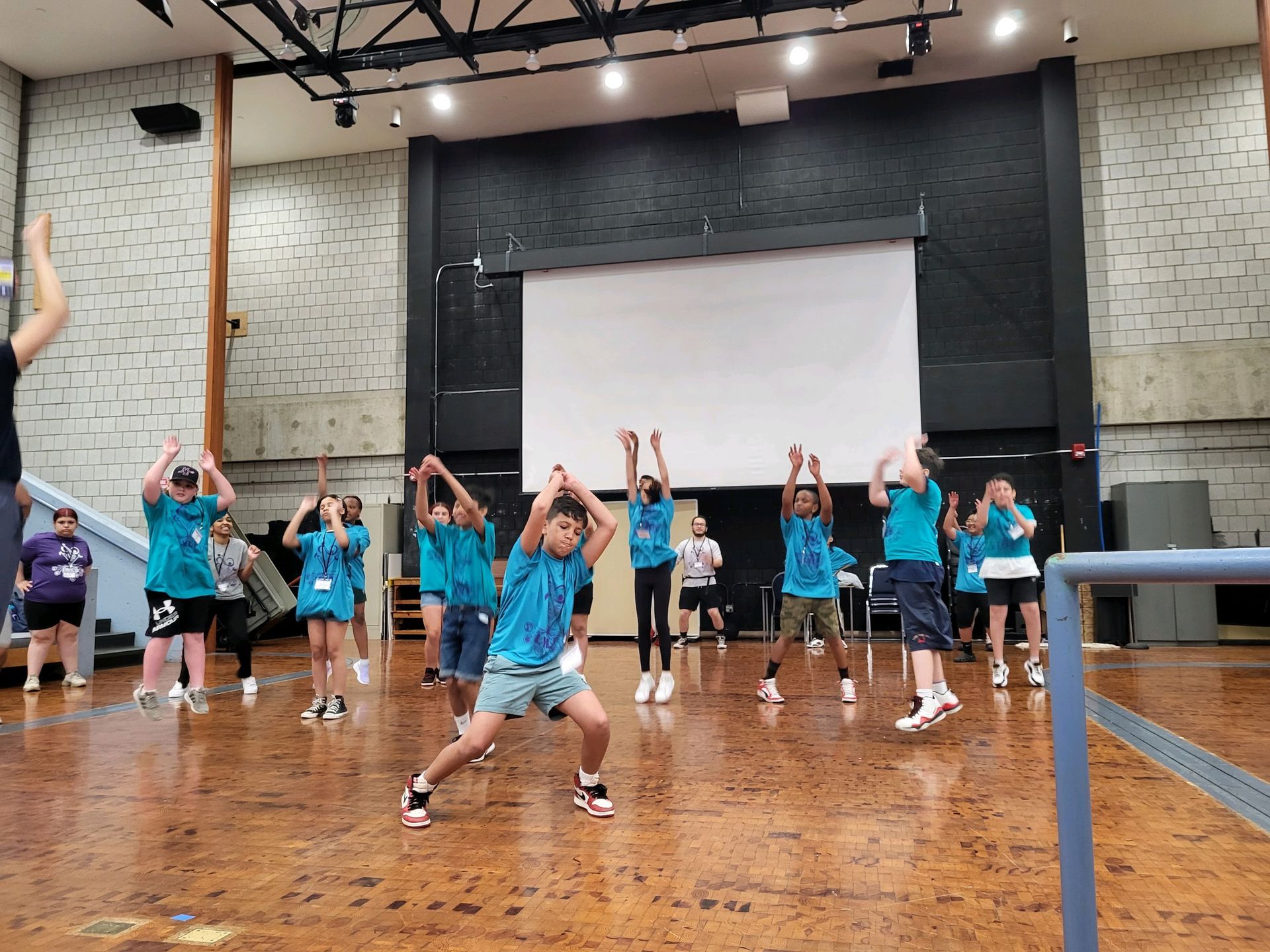 A group of children are dancing in a gym.