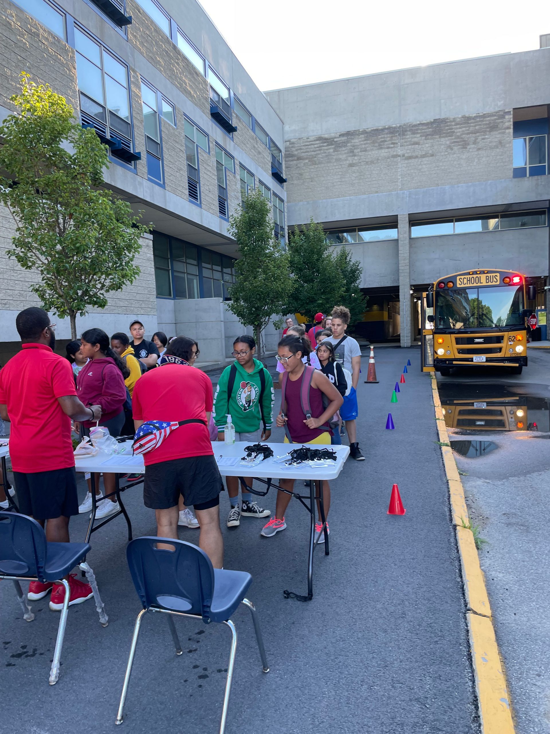 A group of people standing around a table in front of a school bus