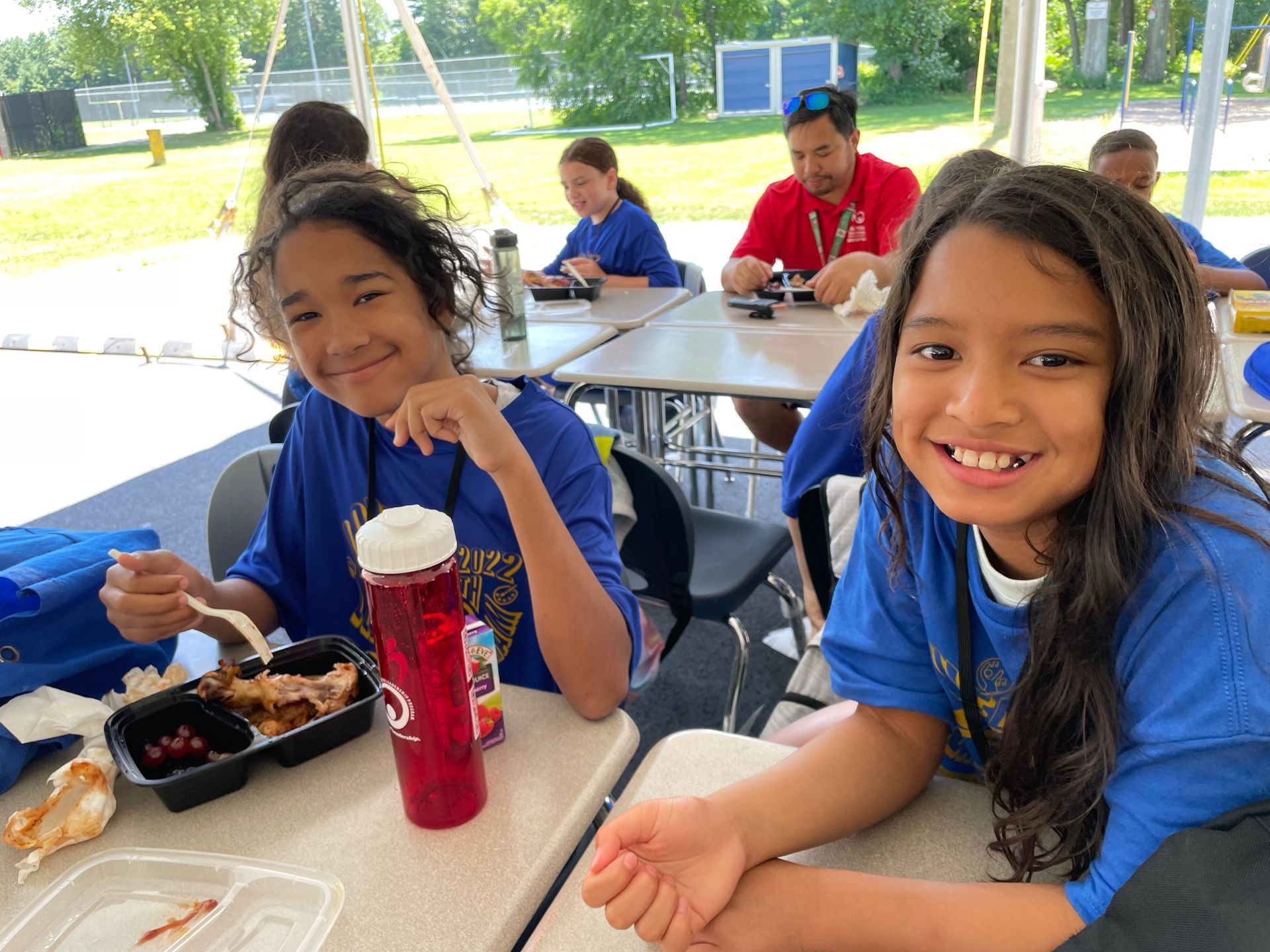 A group of children are sitting at tables eating food.