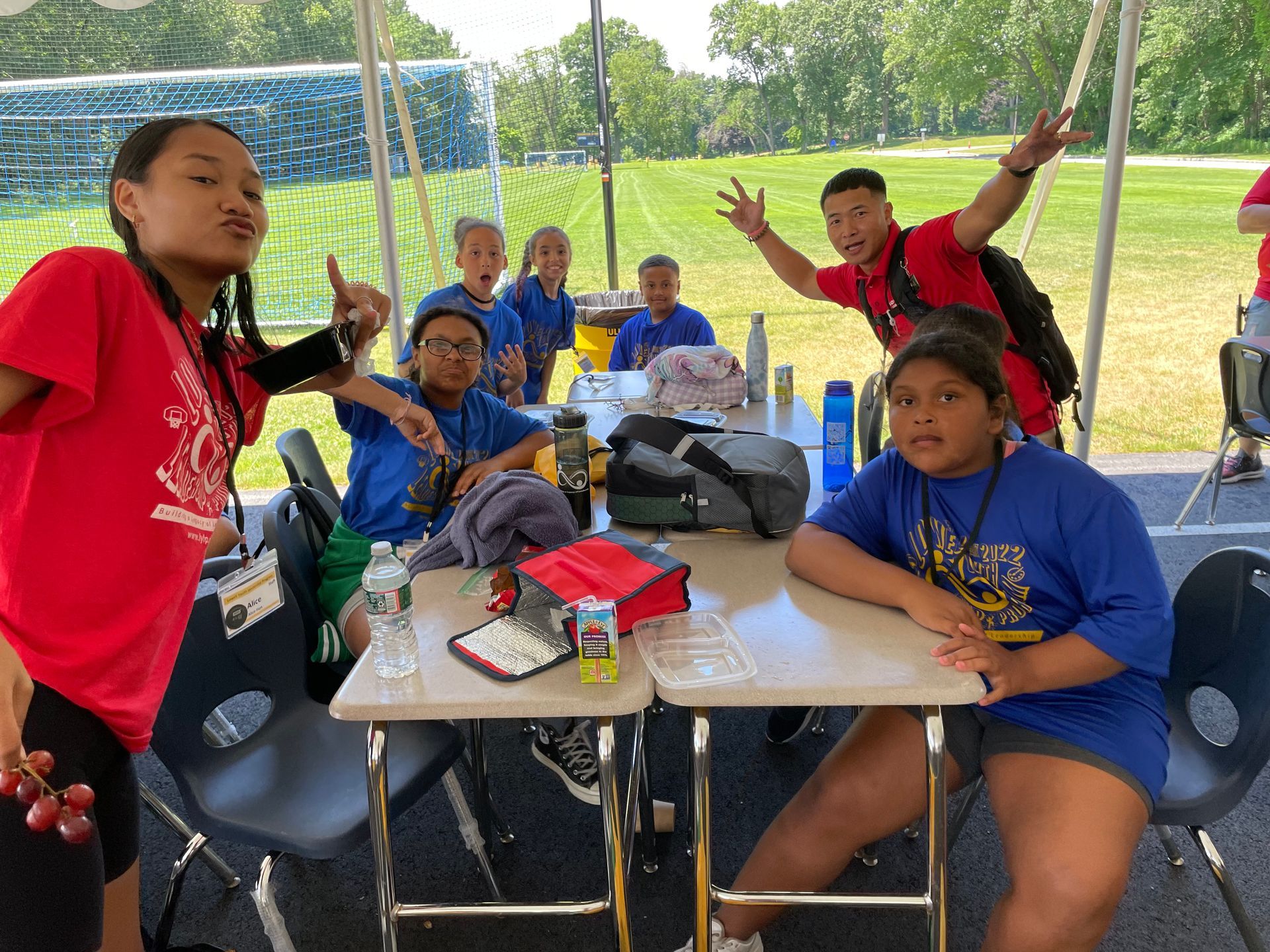 A group of children are sitting at a table under a tent.