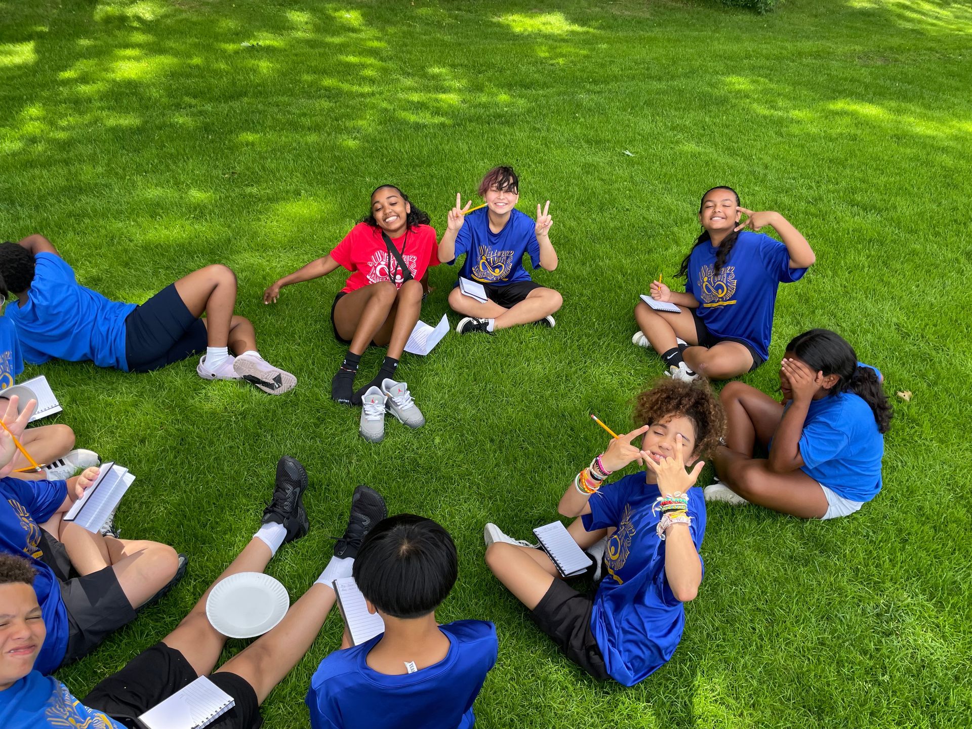 A group of children are sitting in a circle on the grass.