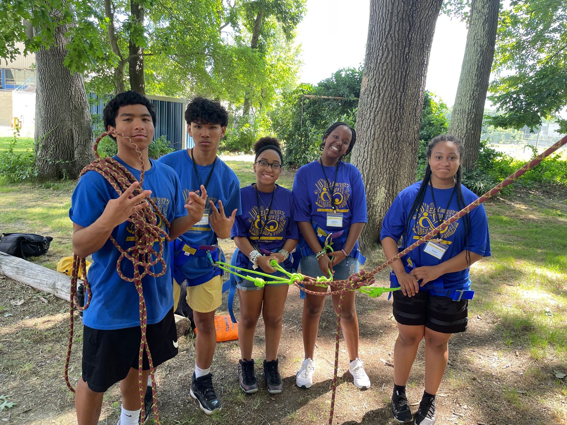 A group of teenagers posing with climbing equipment.