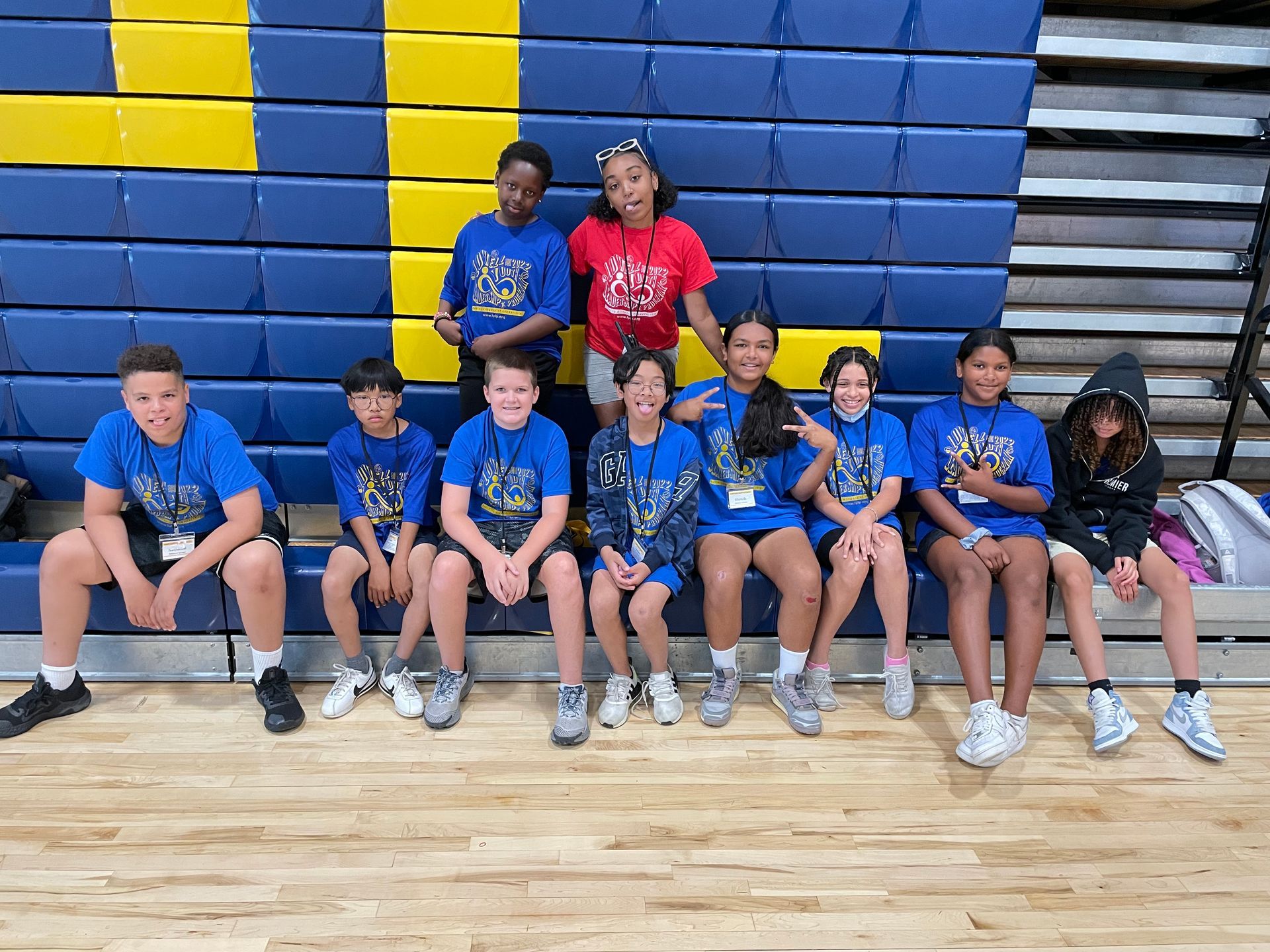 A group of children are sitting on bleachers in a gym.