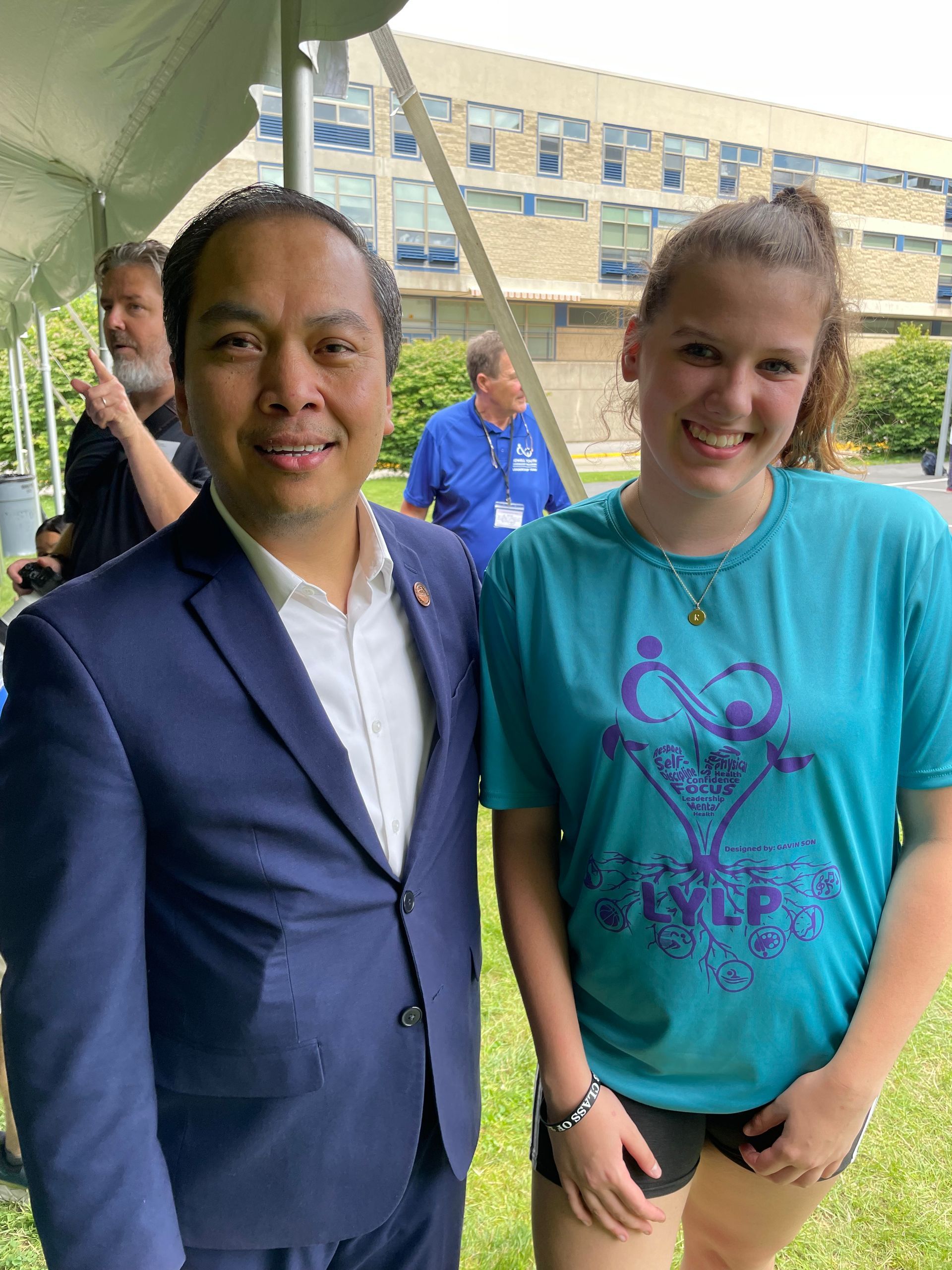 A man in a suit and a woman in a blue shirt are posing for a picture.