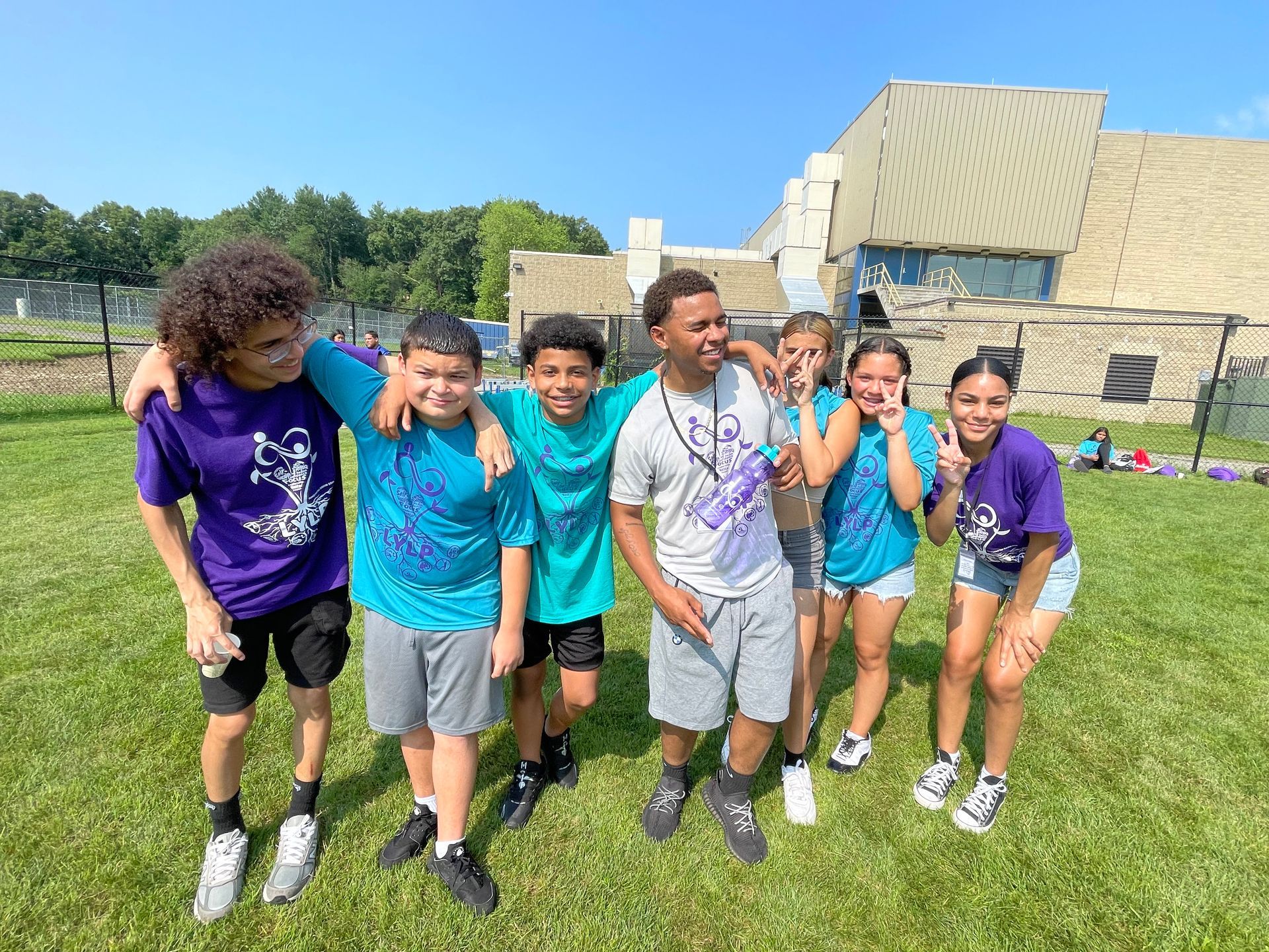 A group of young people are posing for a picture in a field.