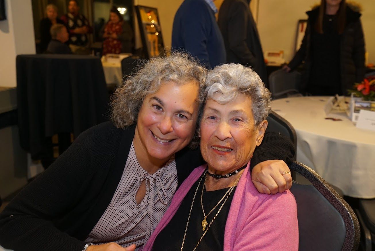 Two women are posing for a picture and one is wearing a pink sweater