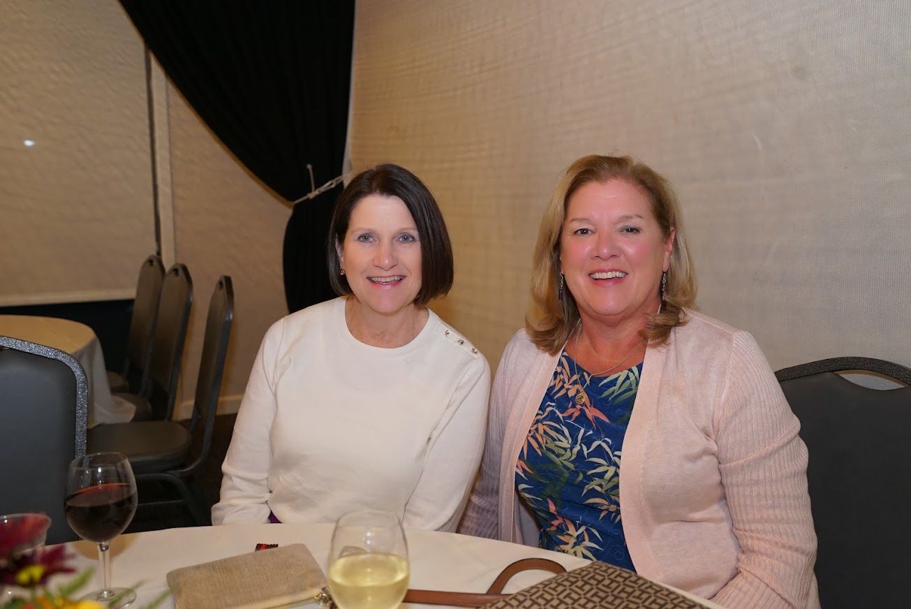 Two women are sitting at a table with wine glasses.