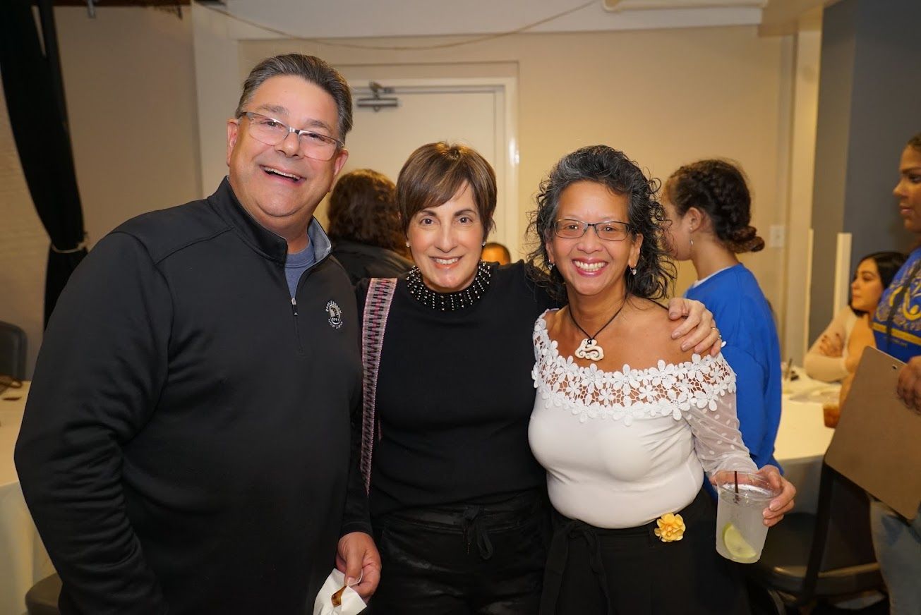 A man and two women are posing for a picture in a room.