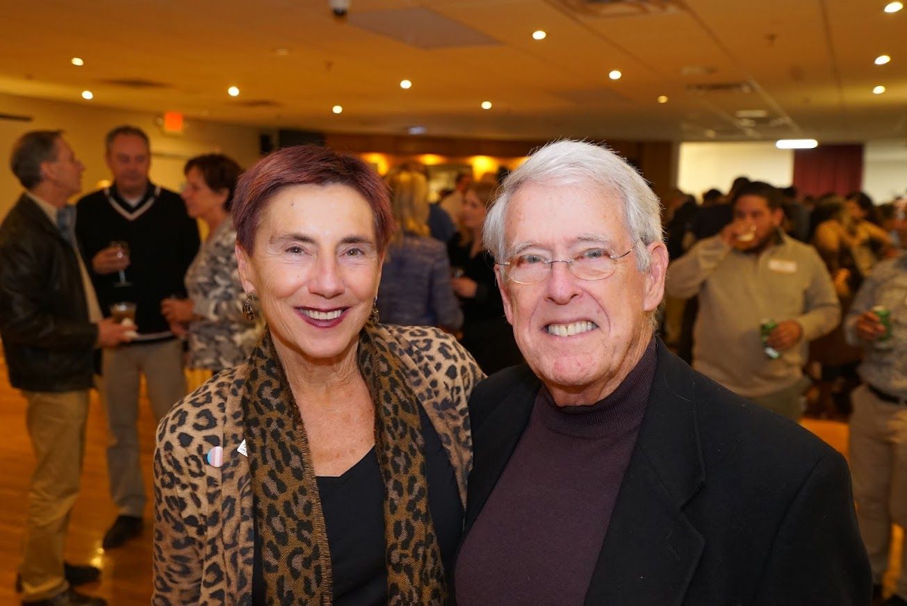 A man and a woman are posing for a picture in a crowded room