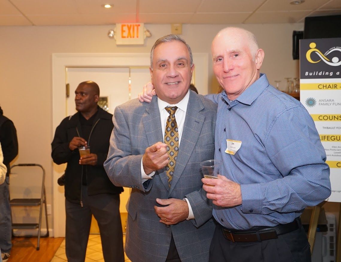 Two men are posing for a picture in front of an exit sign