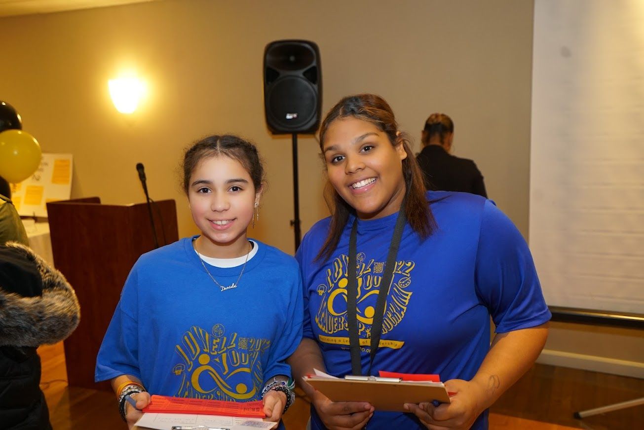 Two girls are posing for a picture in front of a speaker