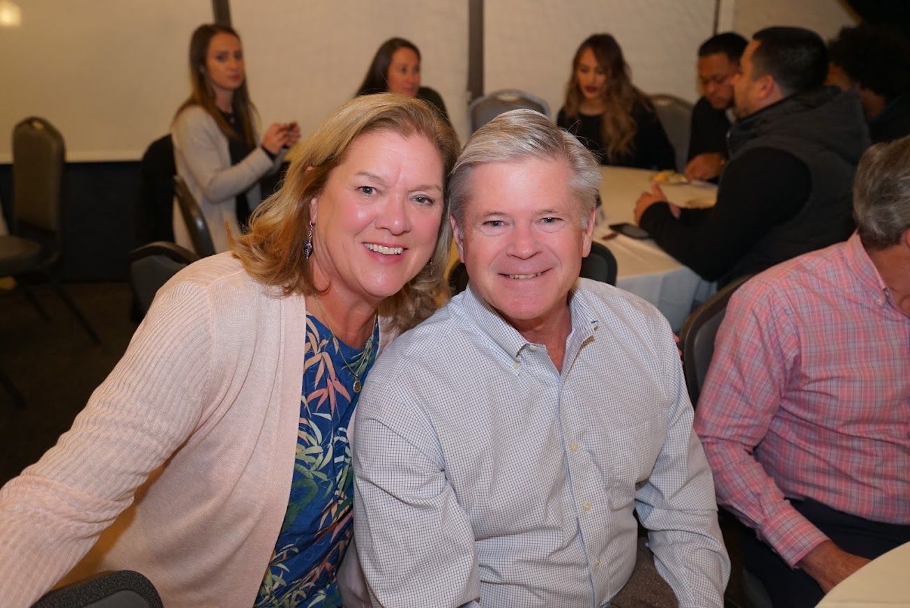 A man and a woman are posing for a picture while sitting at a table.