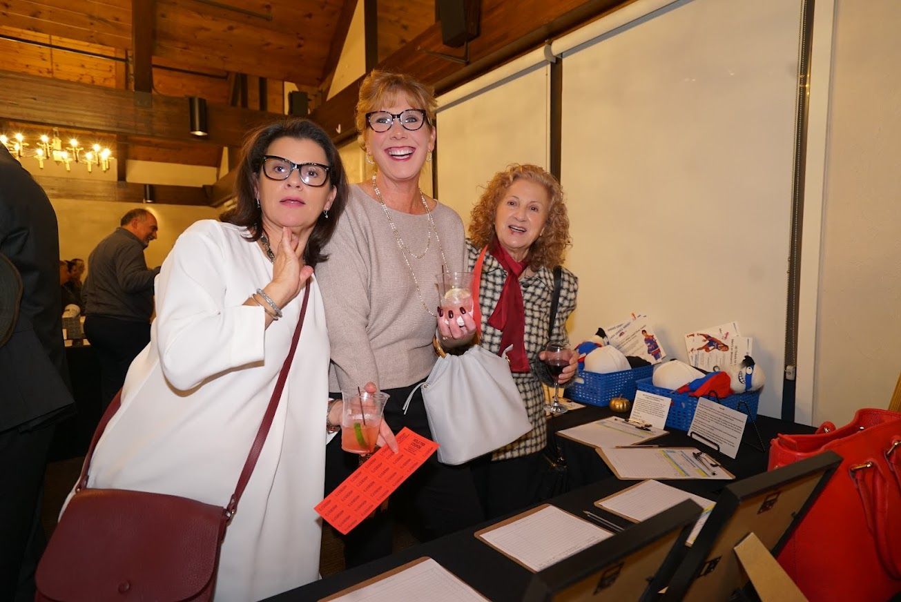 Three women are posing for a picture in front of a table.