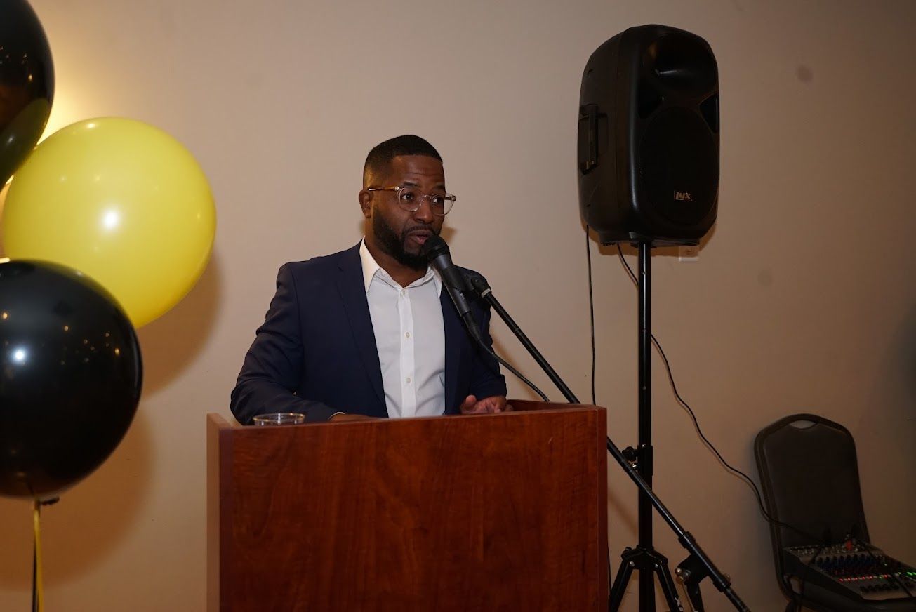 A man is standing at a podium speaking into a microphone.