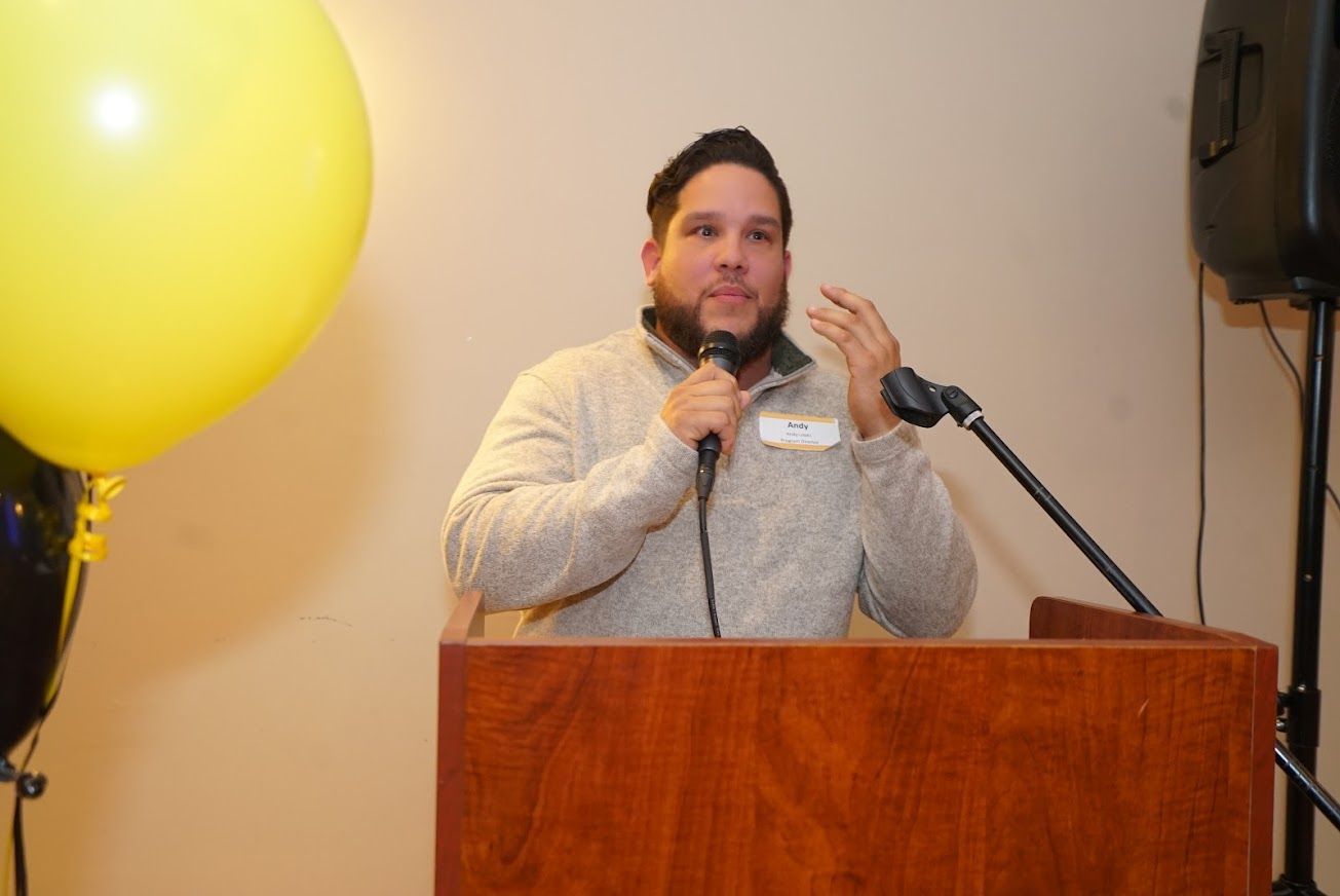 A man is standing at a podium holding a microphone.