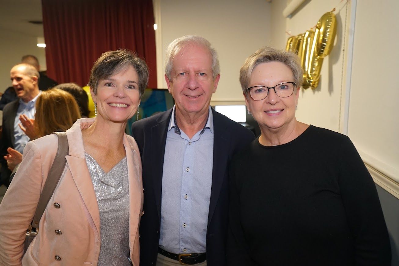 A man and two women are posing for a picture together.