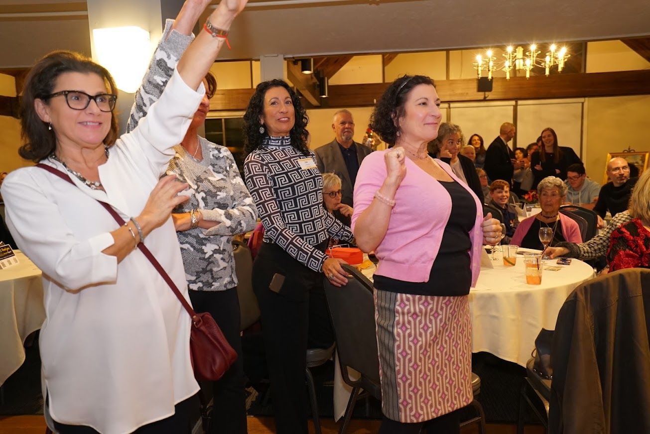 A group of women are standing in a room with their arms in the air.