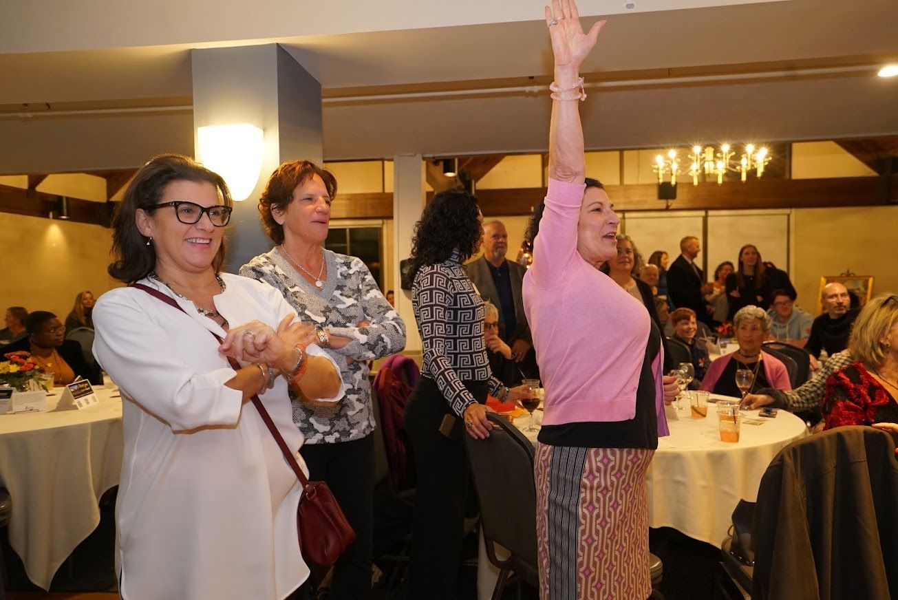 A group of women are standing in a room with their hands in the air.