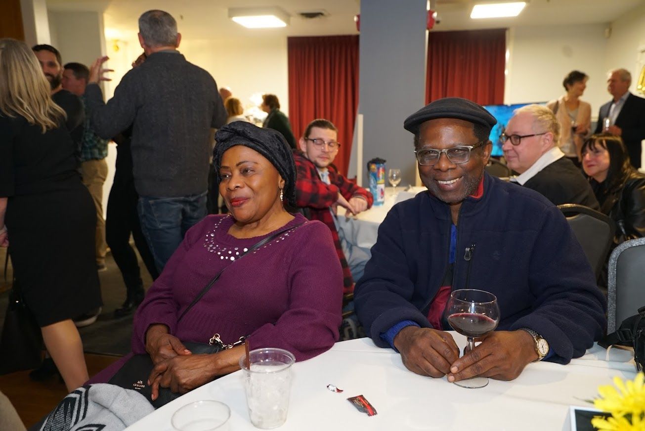 A man and a woman are sitting at a table with glasses of wine.